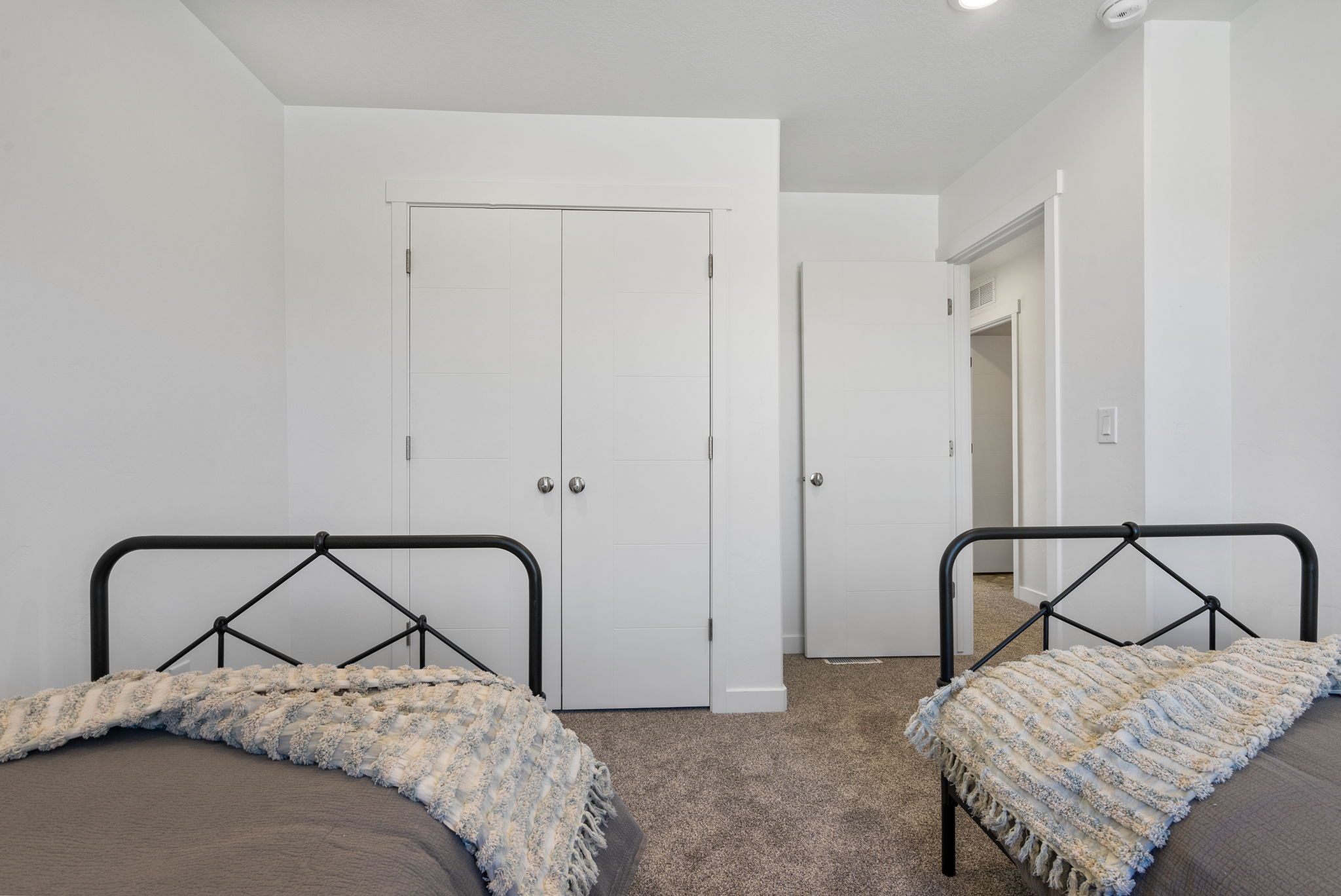 Bedroom featuring neutral wall paint, gray carpet, double-door closet, and white trim