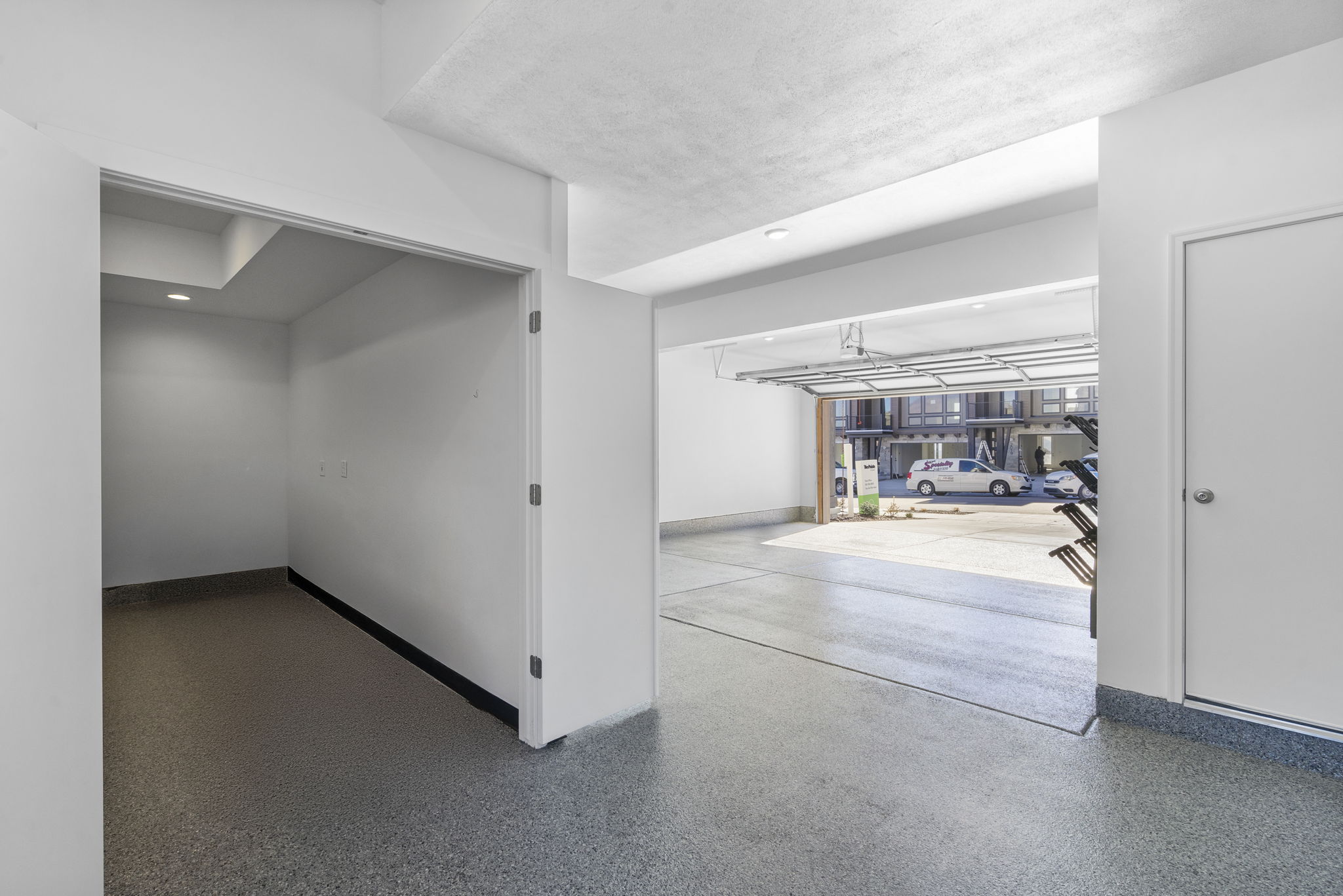 Spacious garage featuring a roll-up door, epoxy flooring, and recessed lighting
