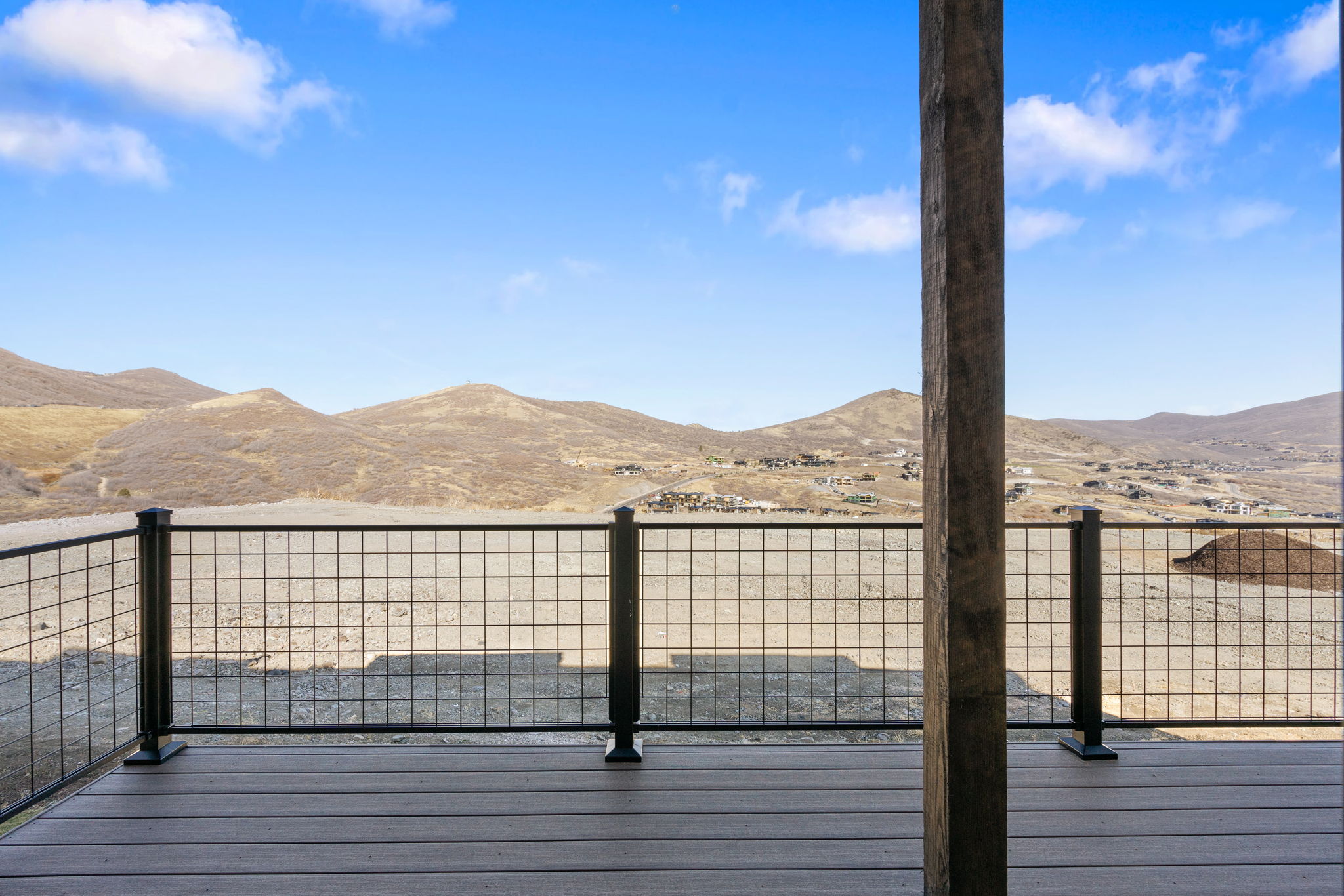 Expansive outdoor deck featuring wood-finish flooring and a black metal grid railing