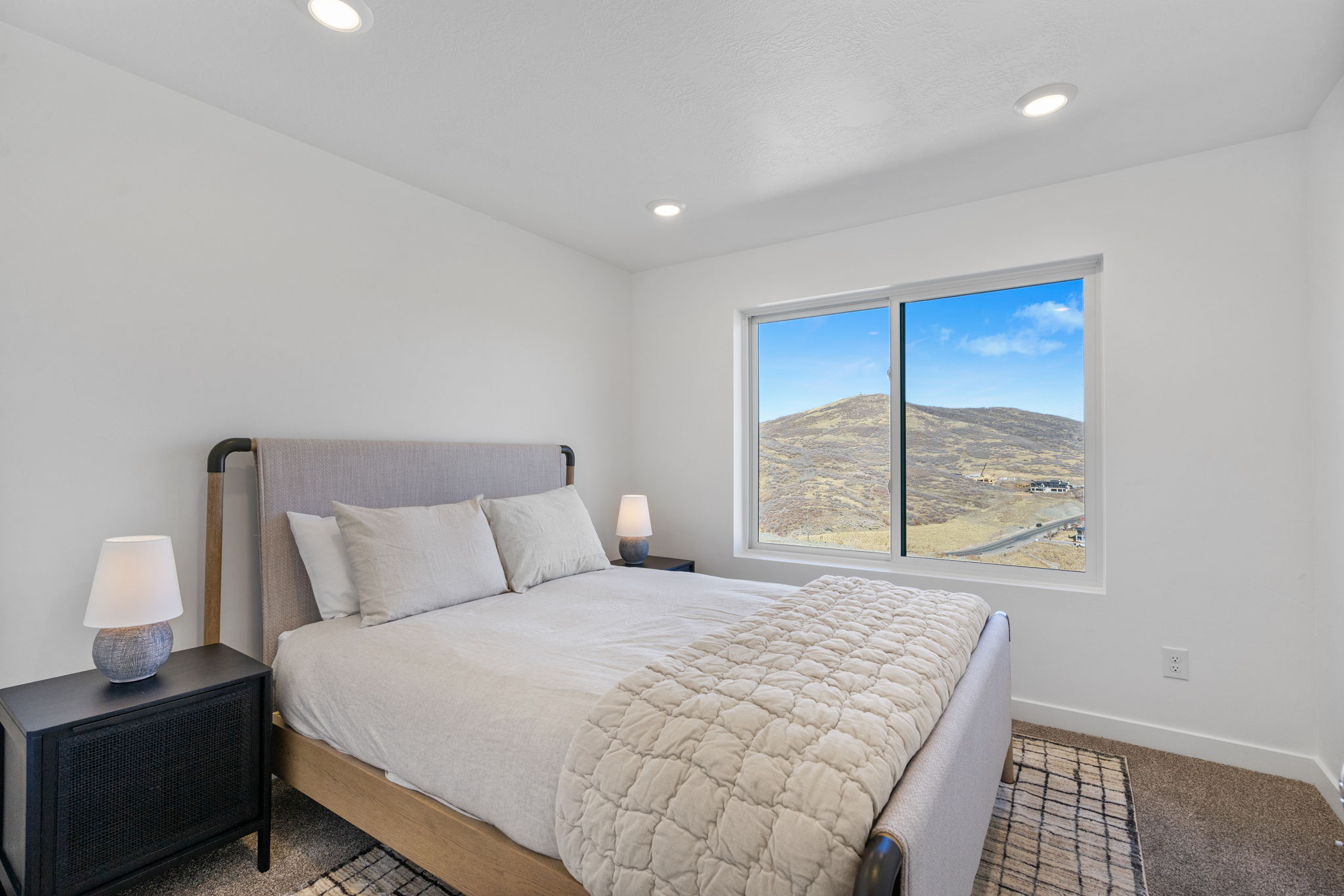 Spacious room featuring a large window with mountain scenery, recessed lighting, and light-toned walls