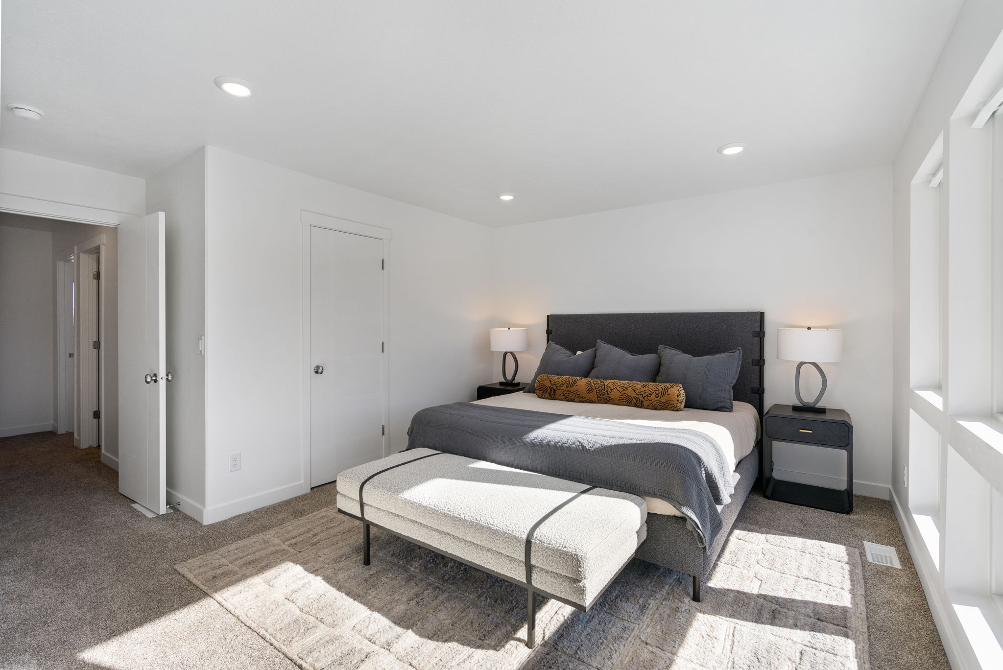 Spacious bedroom featuring multiple windows, recessed lighting, neutral carpet flooring, and white interior doors