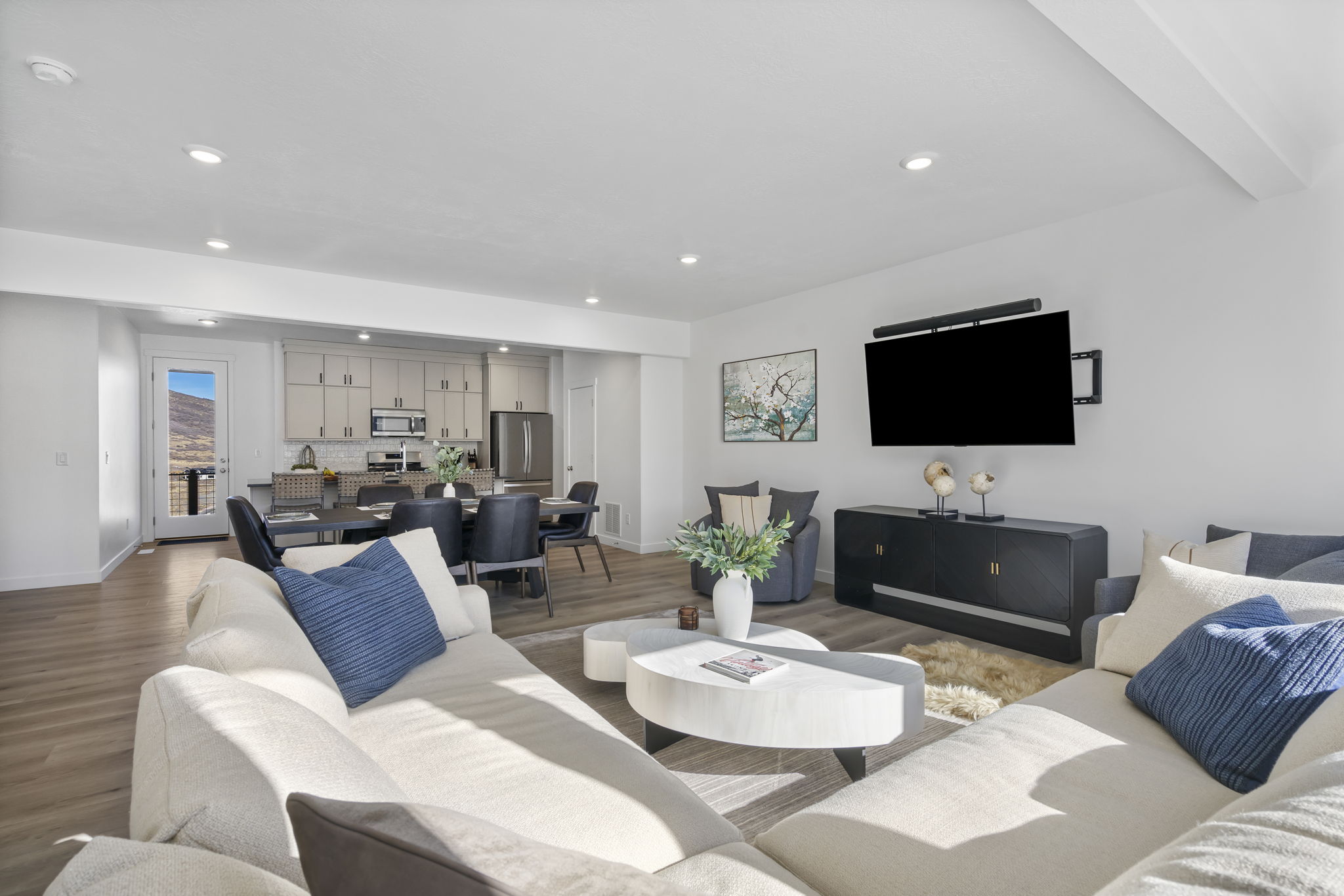 Open-concept living space featuring wood-finish flooring, recessed lighting, and a white color palette