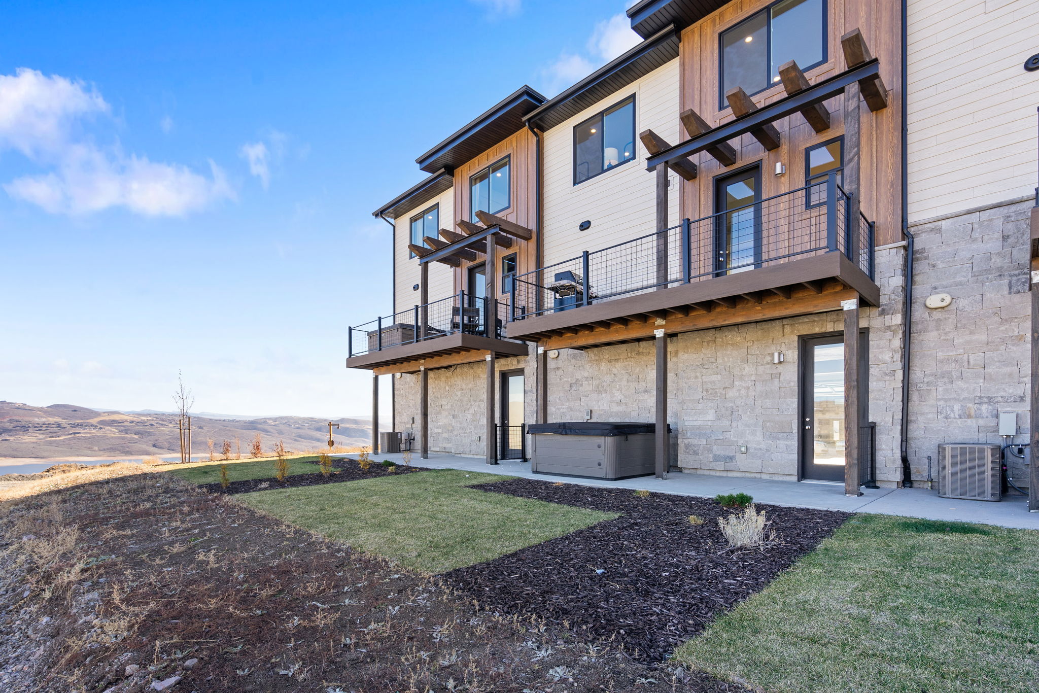 Stone block and wood-finish exterior with a private patio featuring a built-in spa
