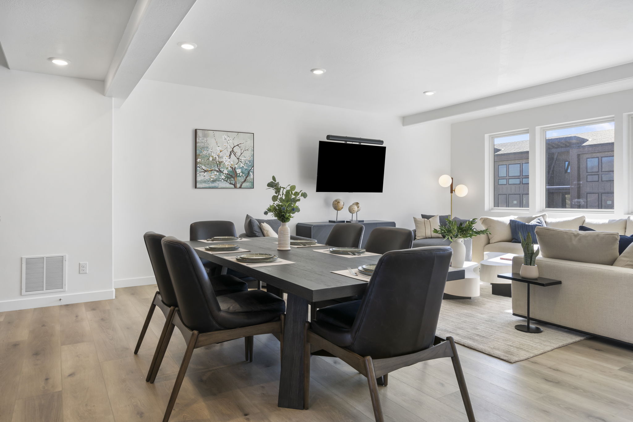 Open-concept living space with light wood-finish flooring, recessed lighting, and large windows