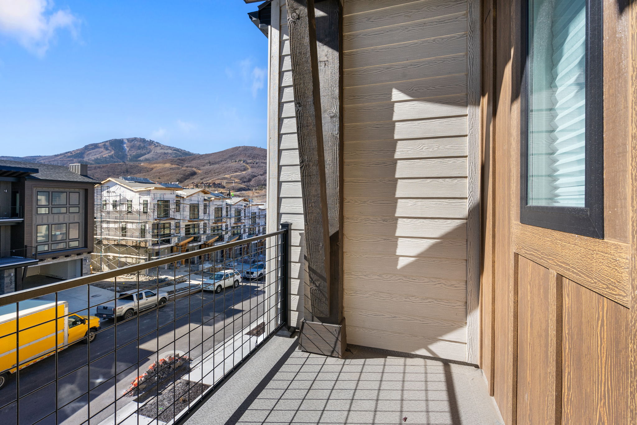 Balcony featuring composite decking, metal grid railing, and wood-paneled siding