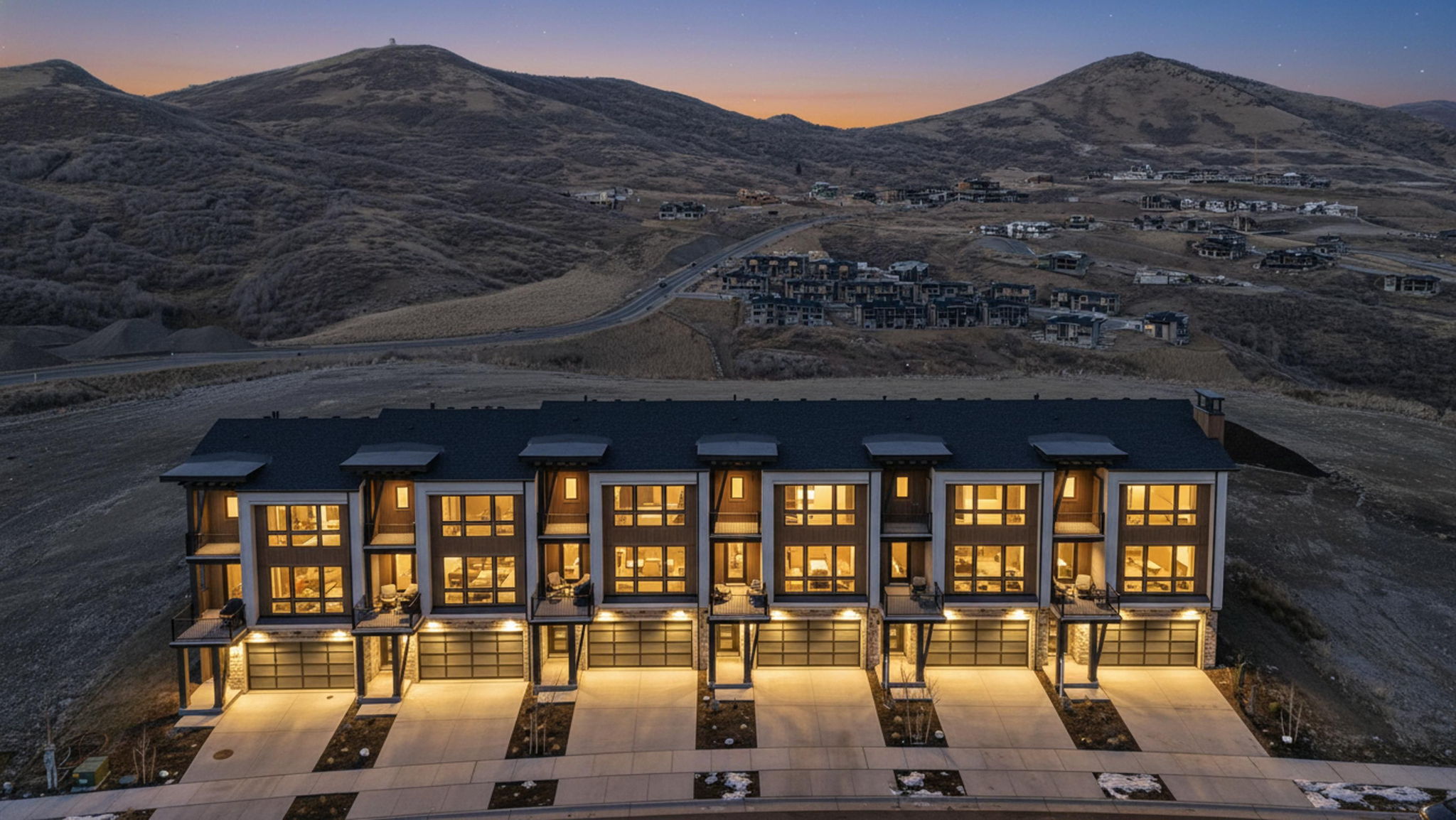 Contemporary townhomes featuring stone and wood-finish siding, multi-panel windows, and individual garages