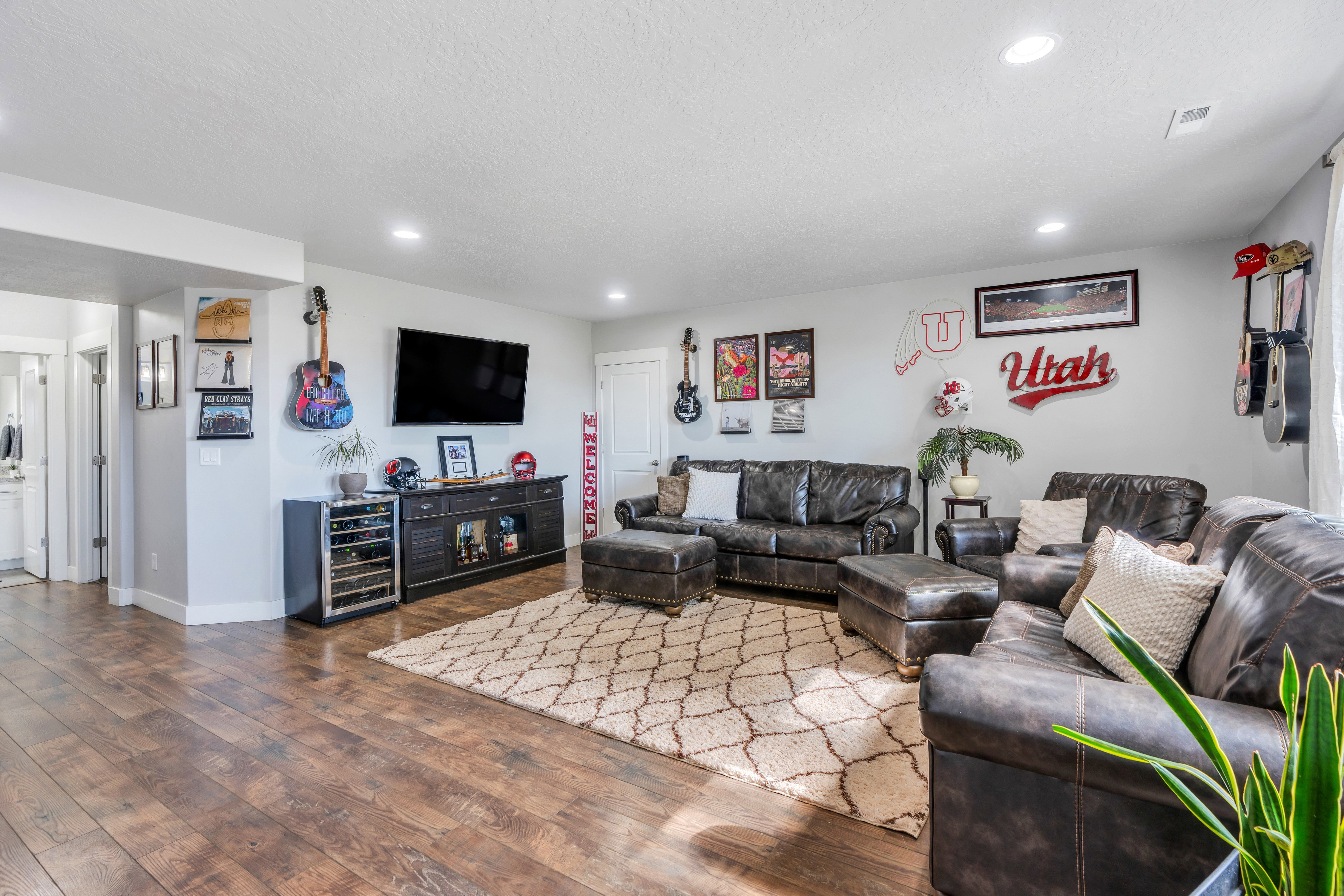 Spacious recreation room featuring wood-finish flooring, recessed lighting, and a built-in media console with integrated beverage refrigeration