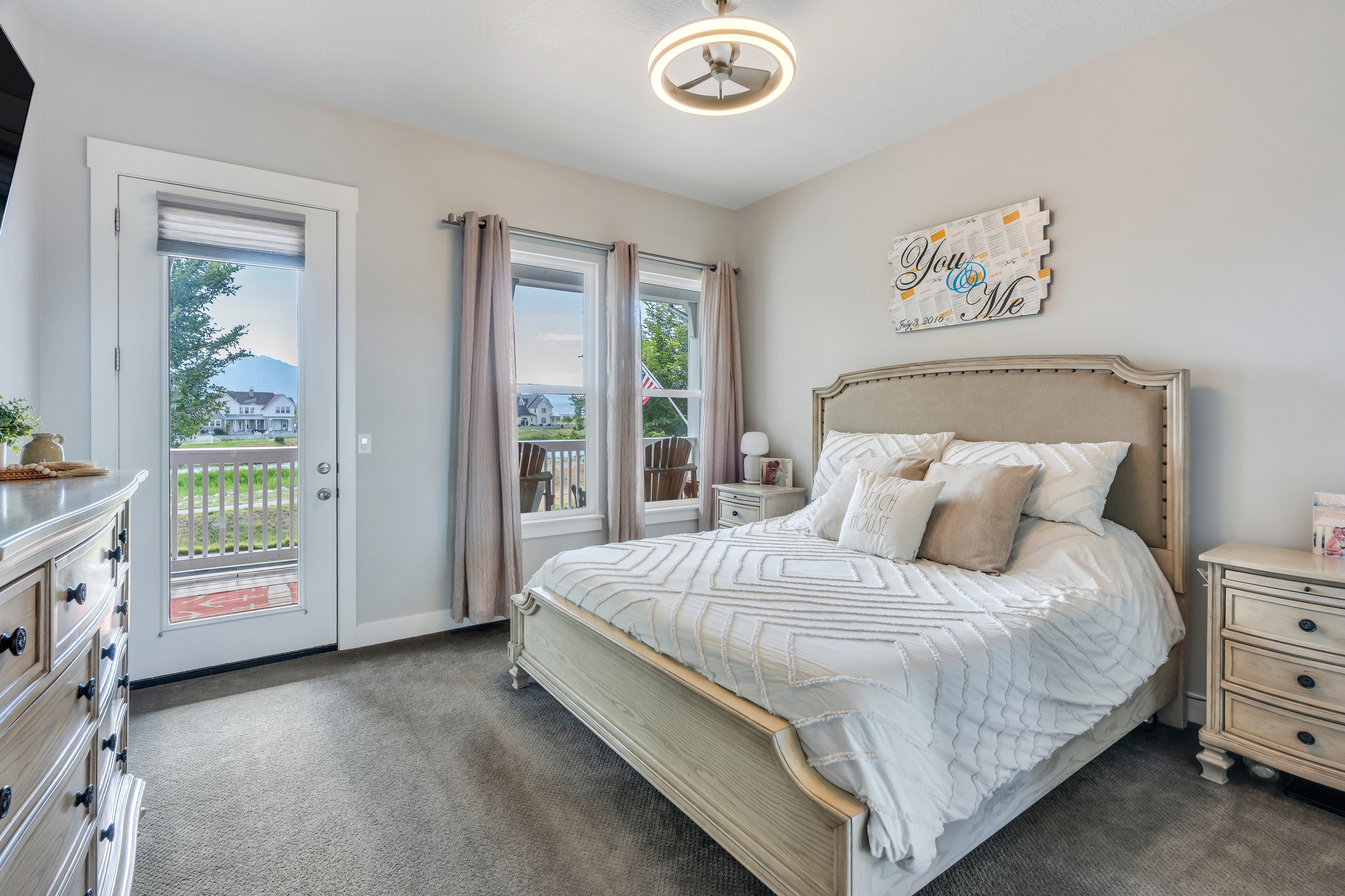 Spacious room featuring light gray wall paint, gray carpet flooring, and a ceiling fan with integrated lighting