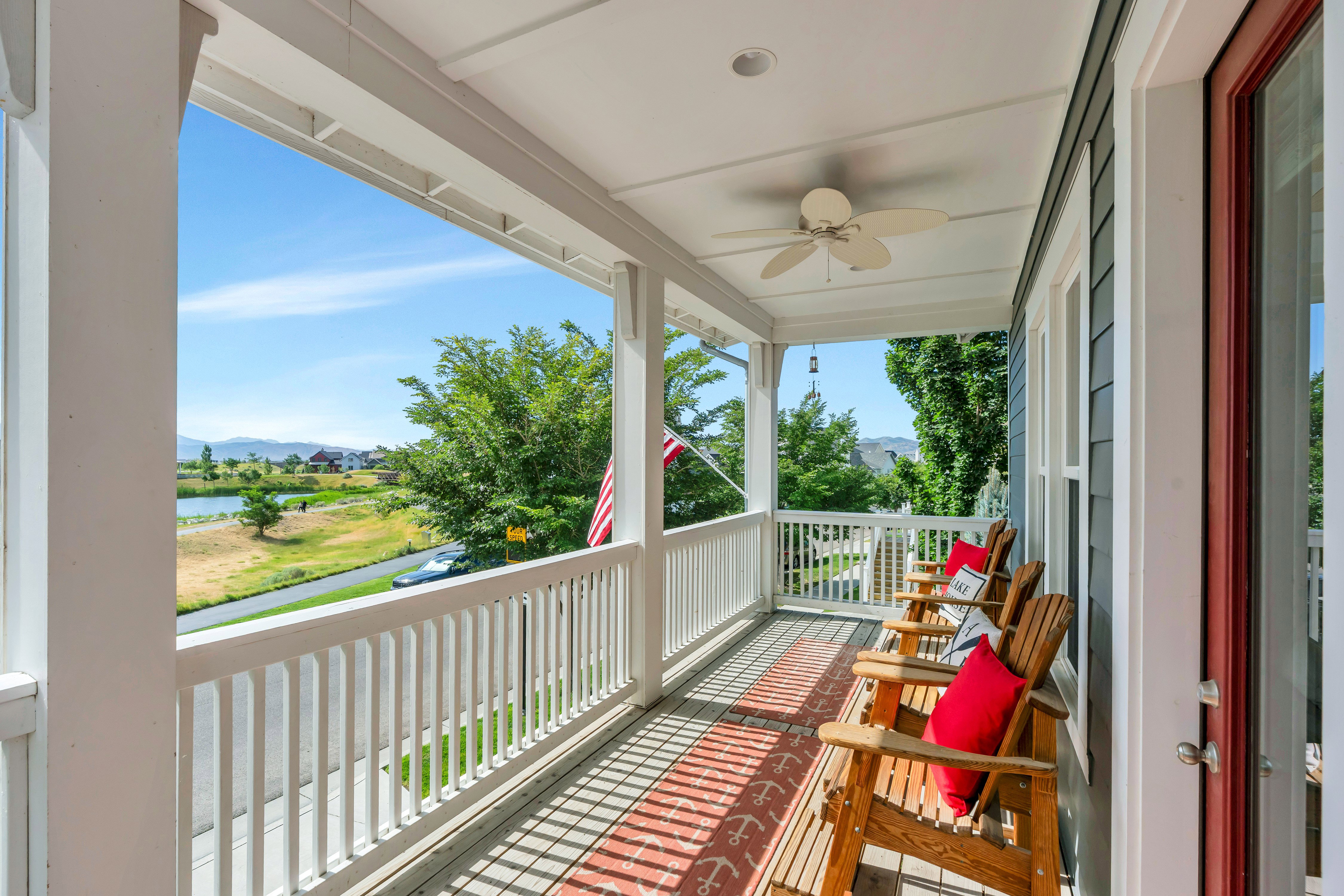 Covered front porch featuring a white spindle railing, wood-finish flooring, and a ceiling fan