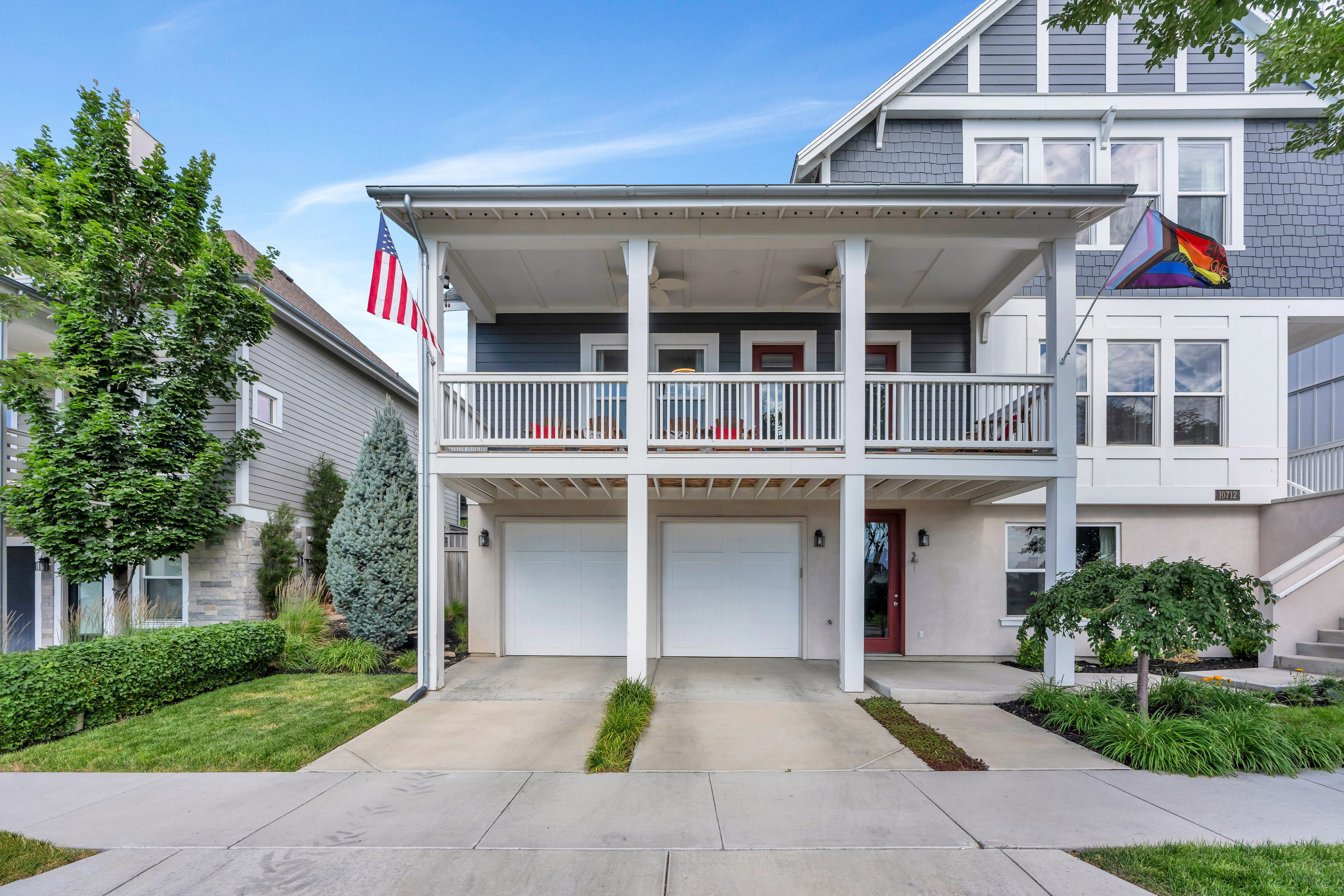 Multi-level residence featuring a two-car garage, dual balconies, and a red entry door