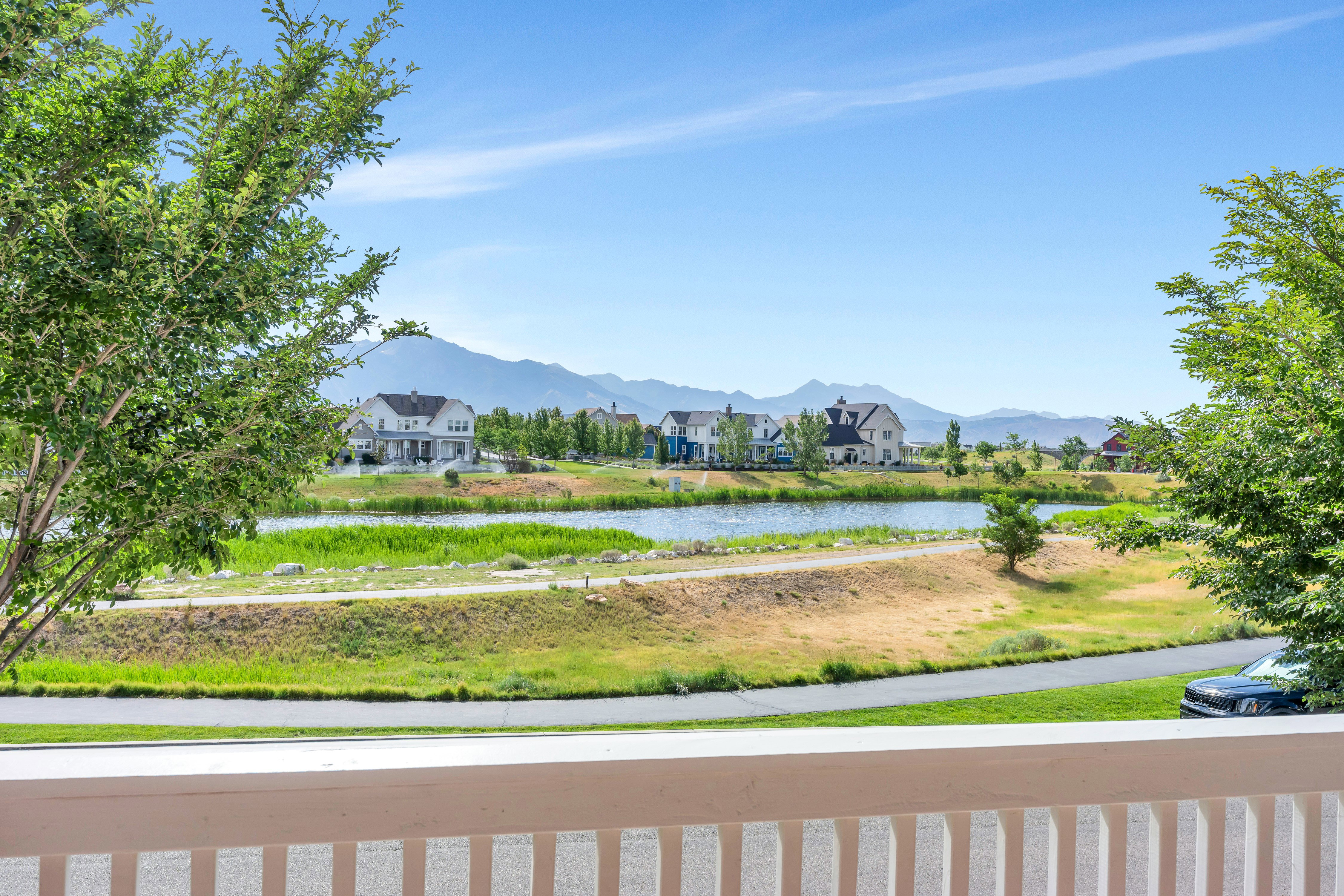 Balcony offering broad outdoor scenery, featuring a prominent body of water, distant mountain range, and surrounding greenery