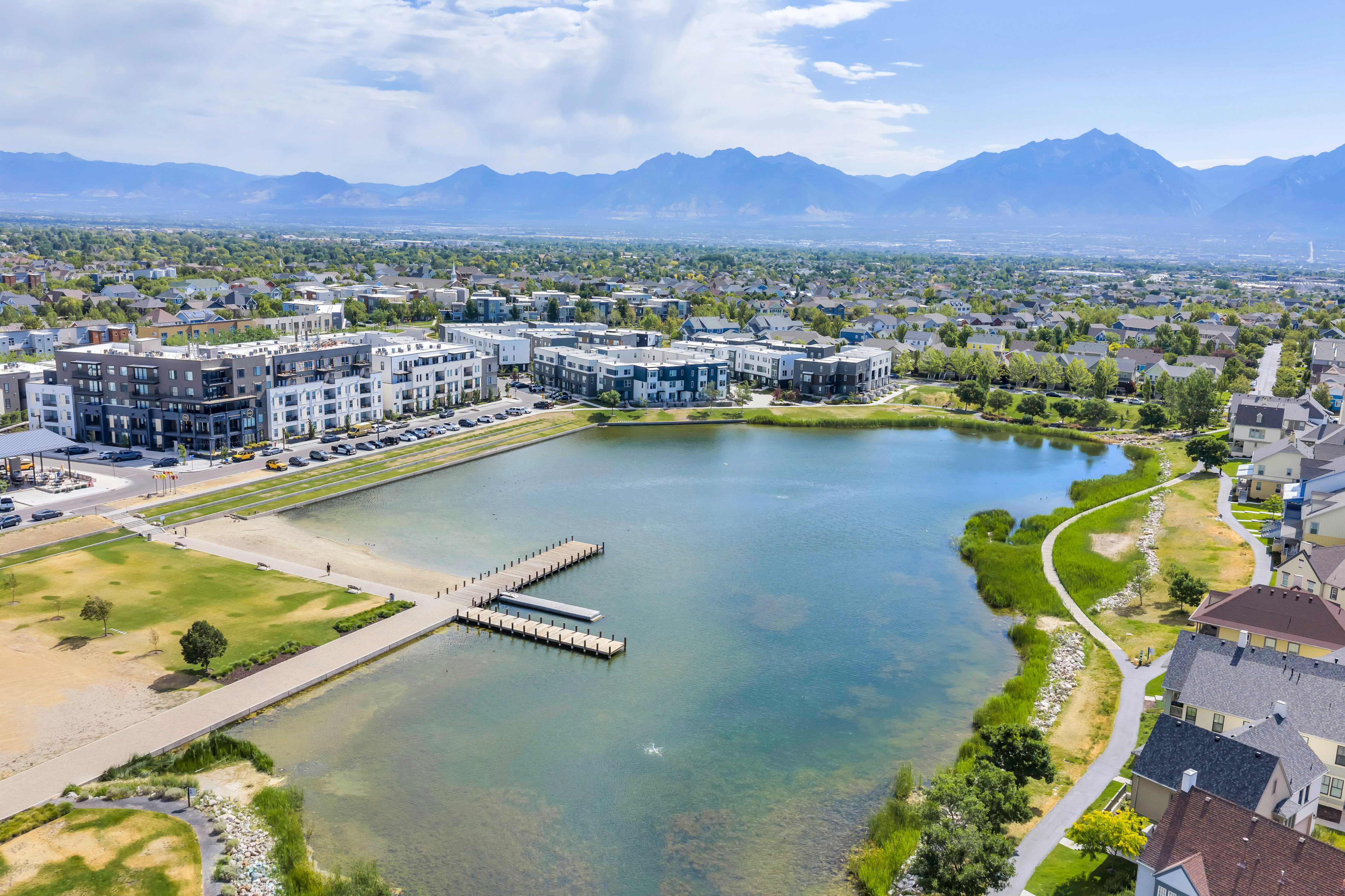 Expansive lake featuring a dock, surrounding green spaces, and walking paths