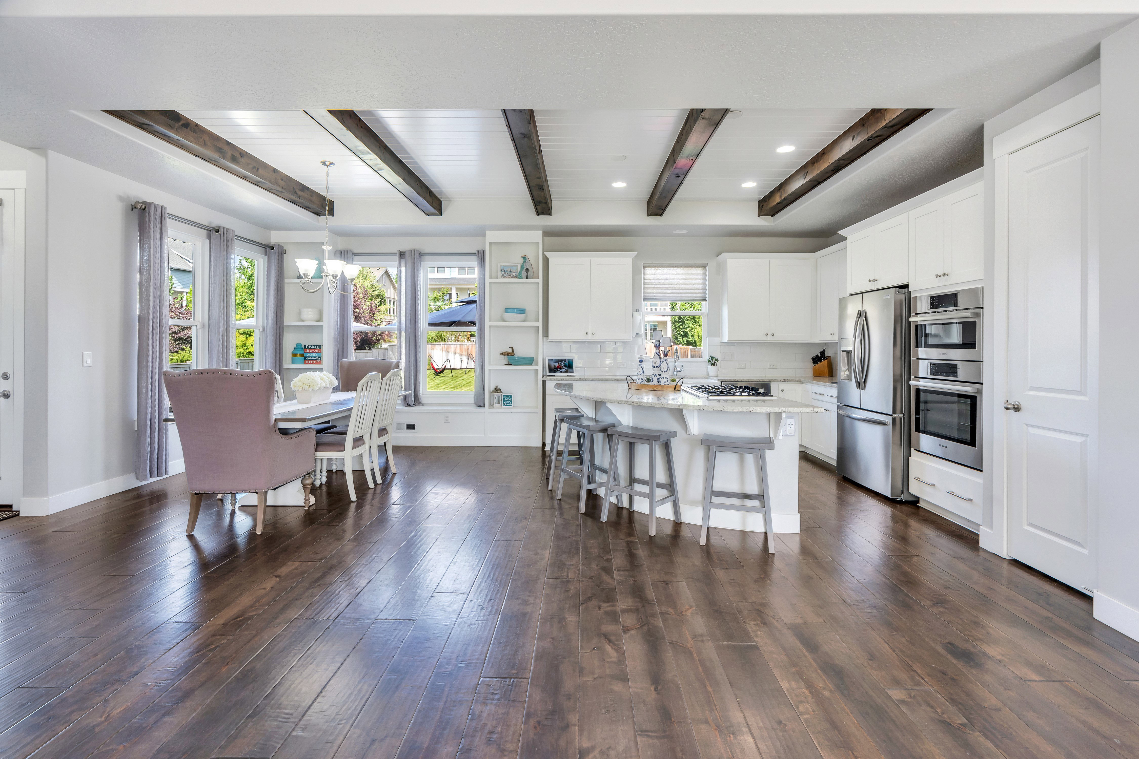 Spacious kitchen and dining area featuring dark wood-finish flooring and exposed ceiling beams