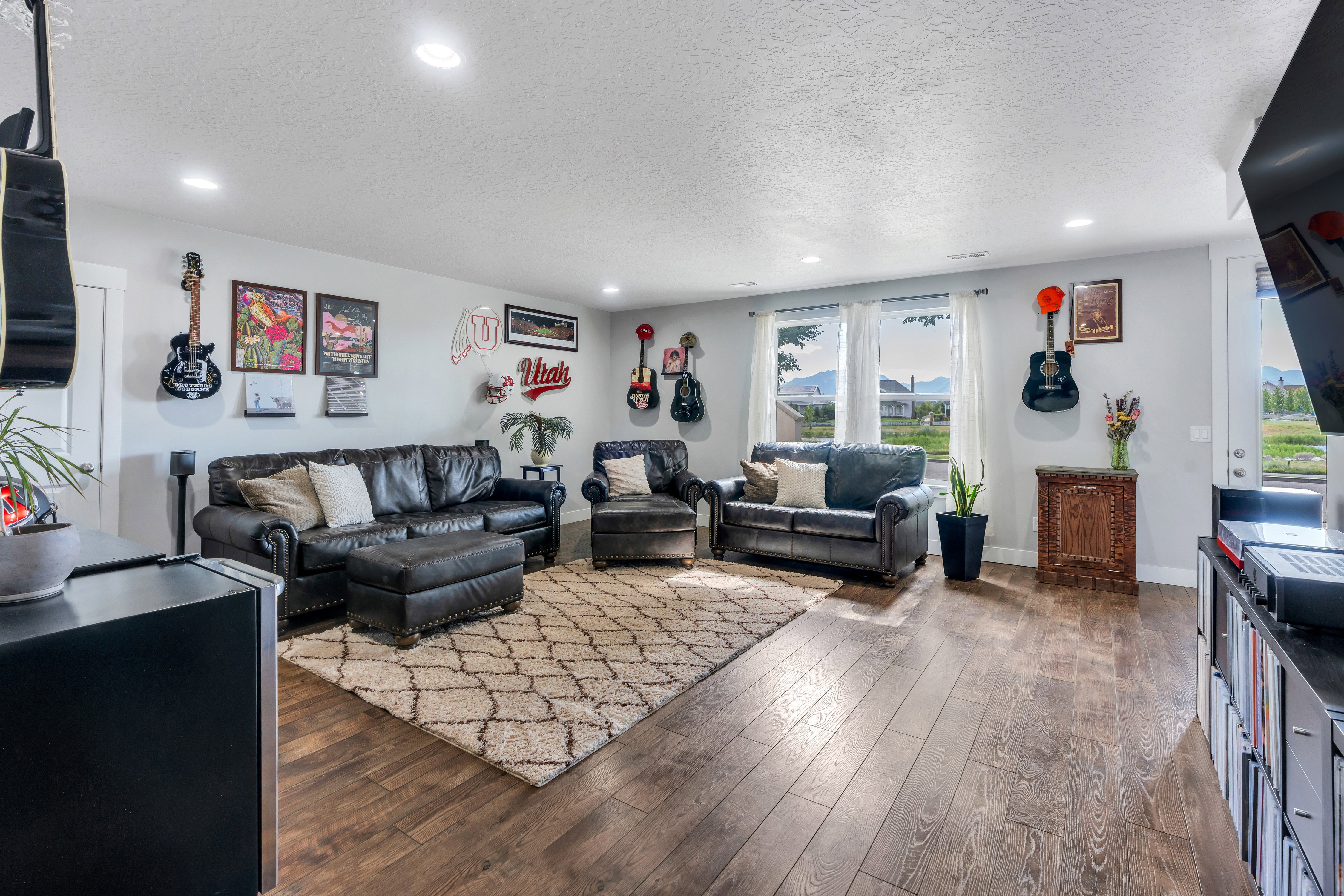 Spacious living area featuring wood-finish flooring, recessed lighting, and large windows with outdoor scenery