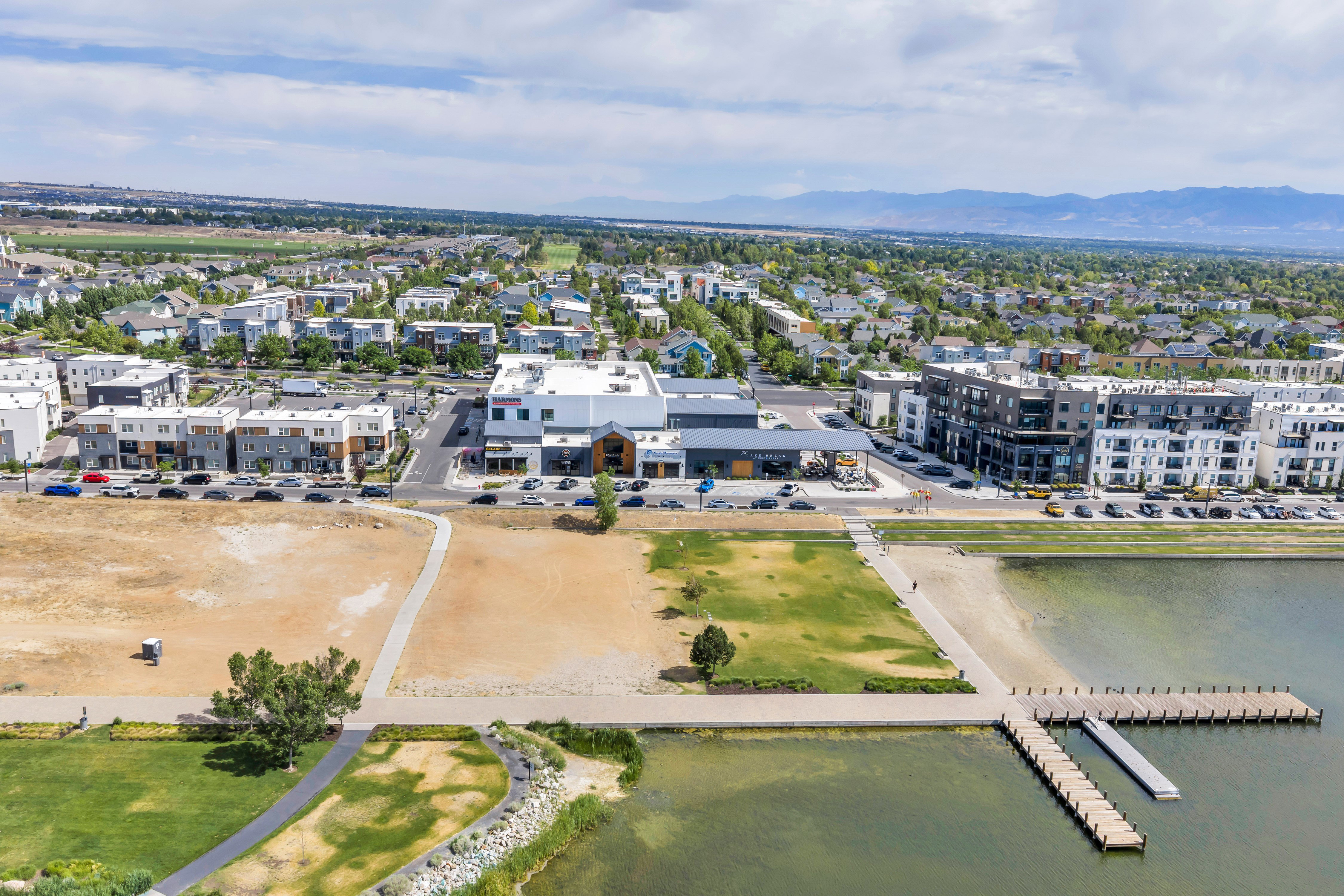 Expansive aerial perspective showcasing a residential and commercial development alongside a body of water