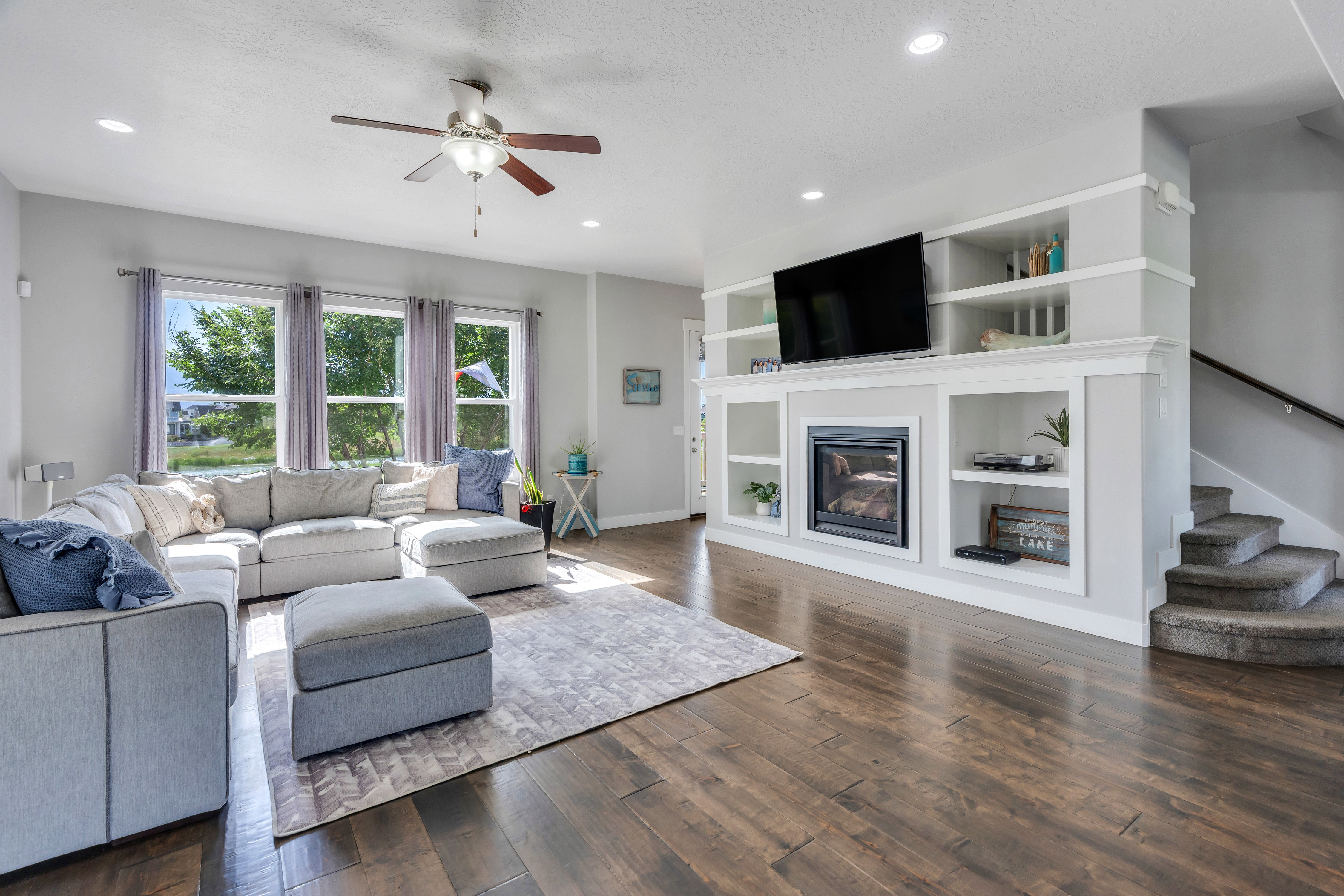 Spacious living area featuring wood-finish flooring, a ceiling fan, and recessed lighting