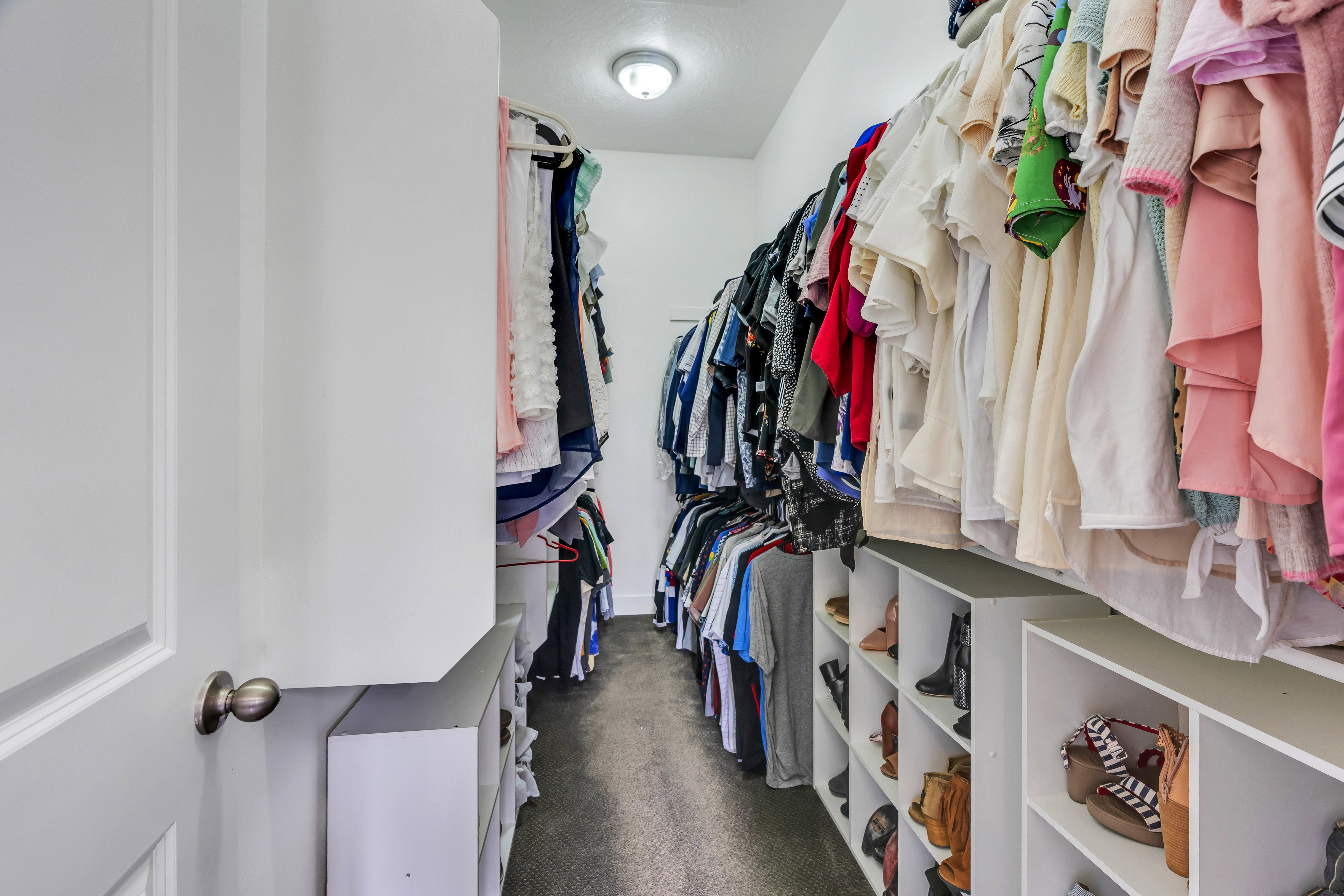 Walk-in closet featuring white built-in shelving, multiple hanging rods, and recessed ceiling lighting