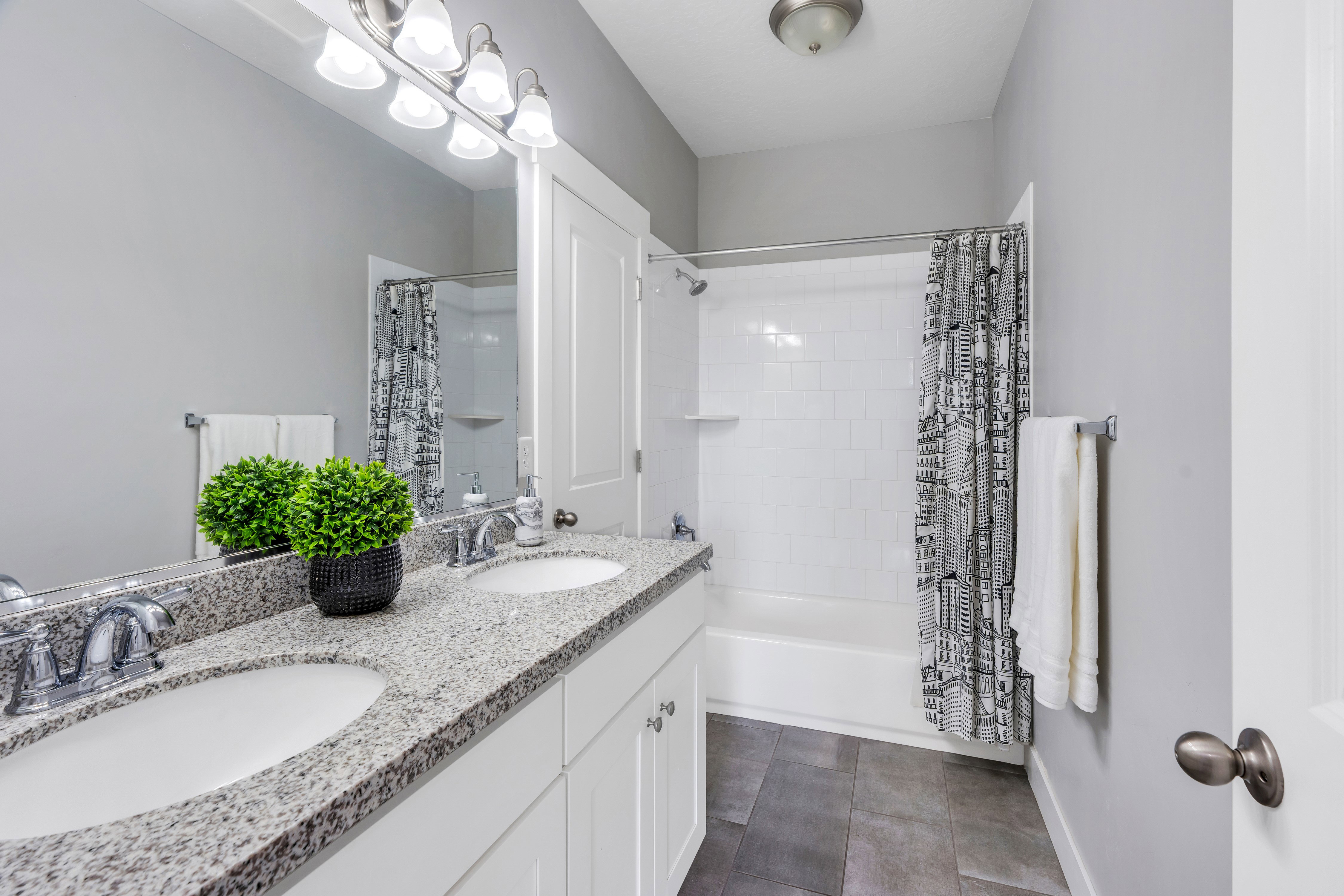 Dual vanity with granite-style countertop, white cabinetry, and chrome fixtures