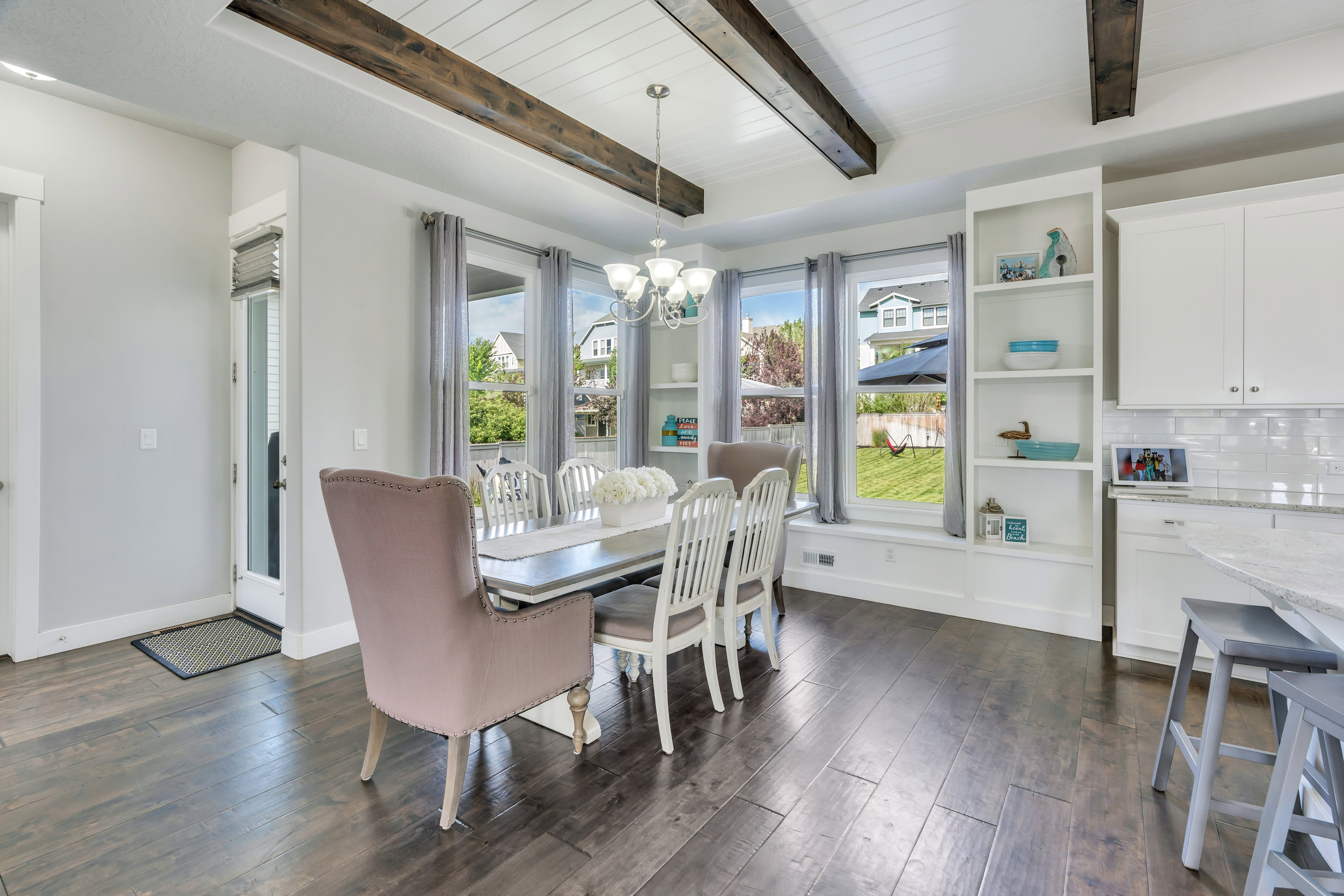 Dining area featuring wood-finish flooring, a white coffered ceiling with dark exposed beams, and a multi-light chandelier