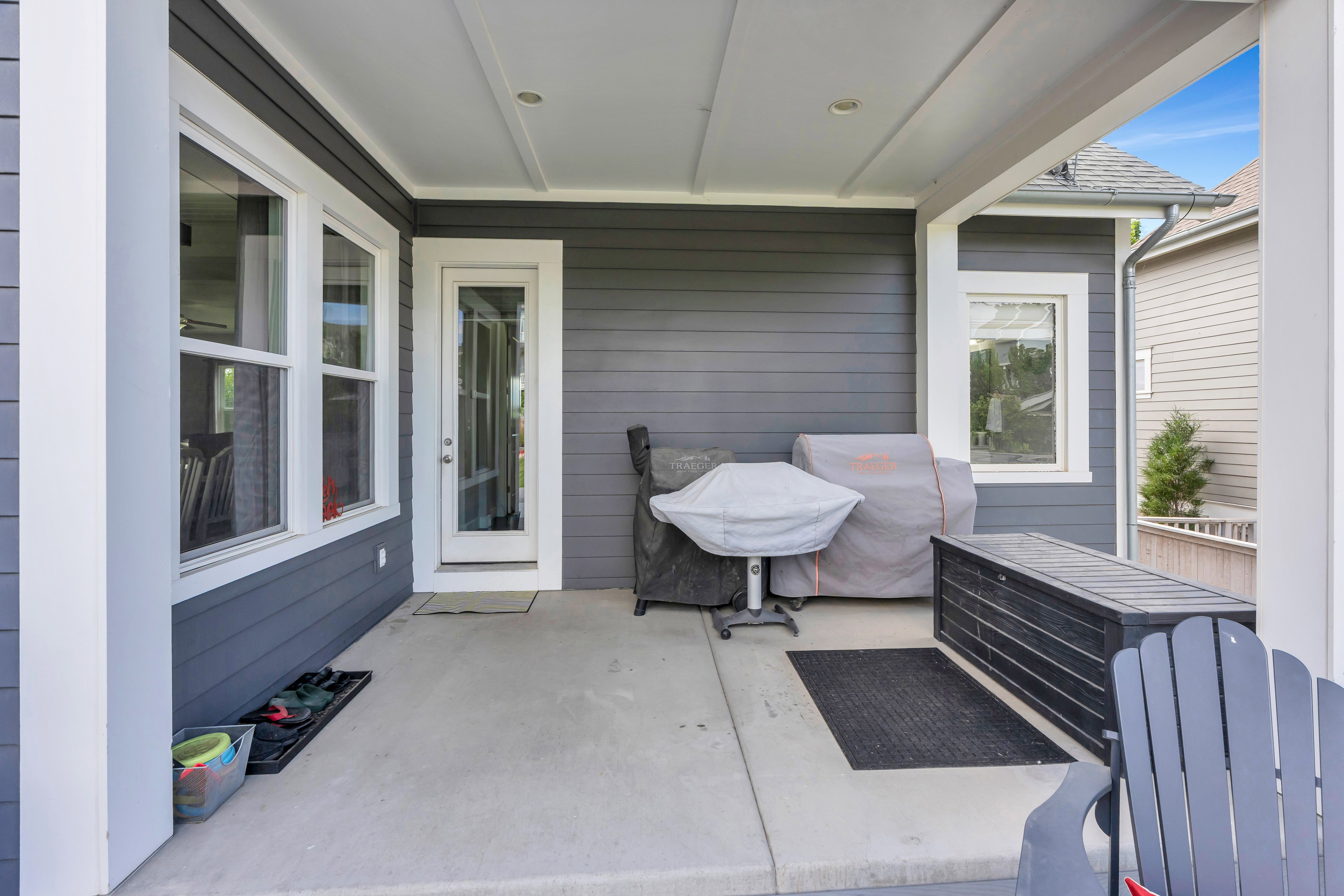Covered concrete patio featuring dark gray horizontal siding and white trim