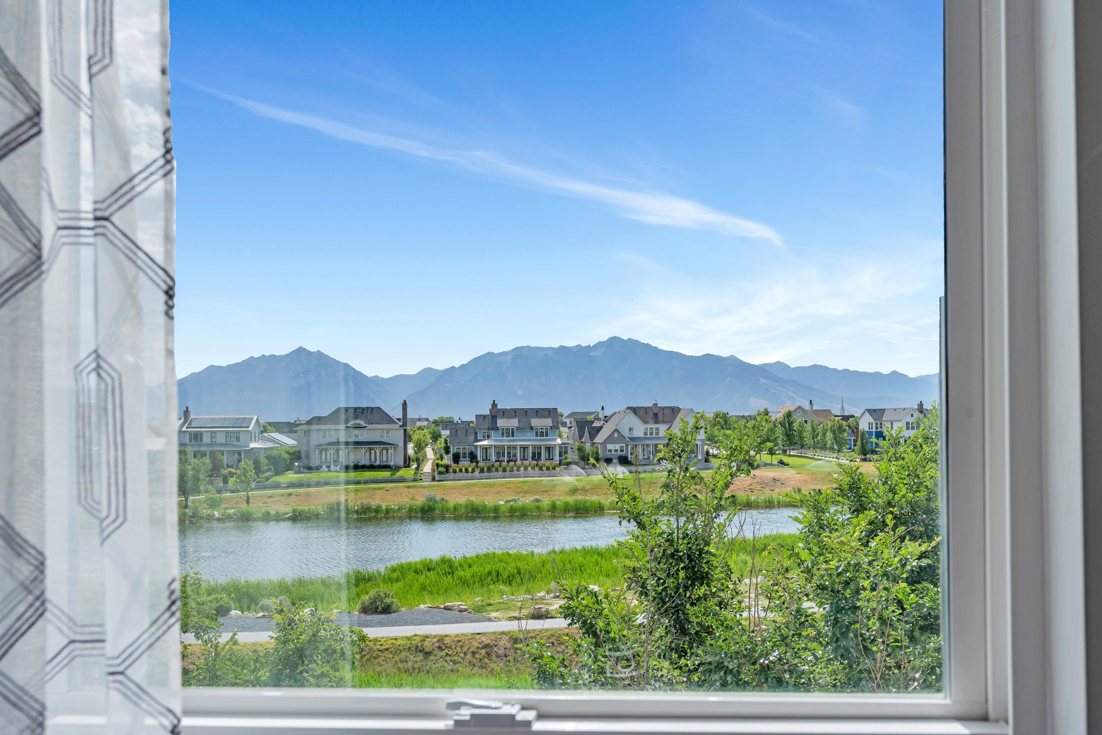 Window framing a lake, distant mountain range, and residential properties