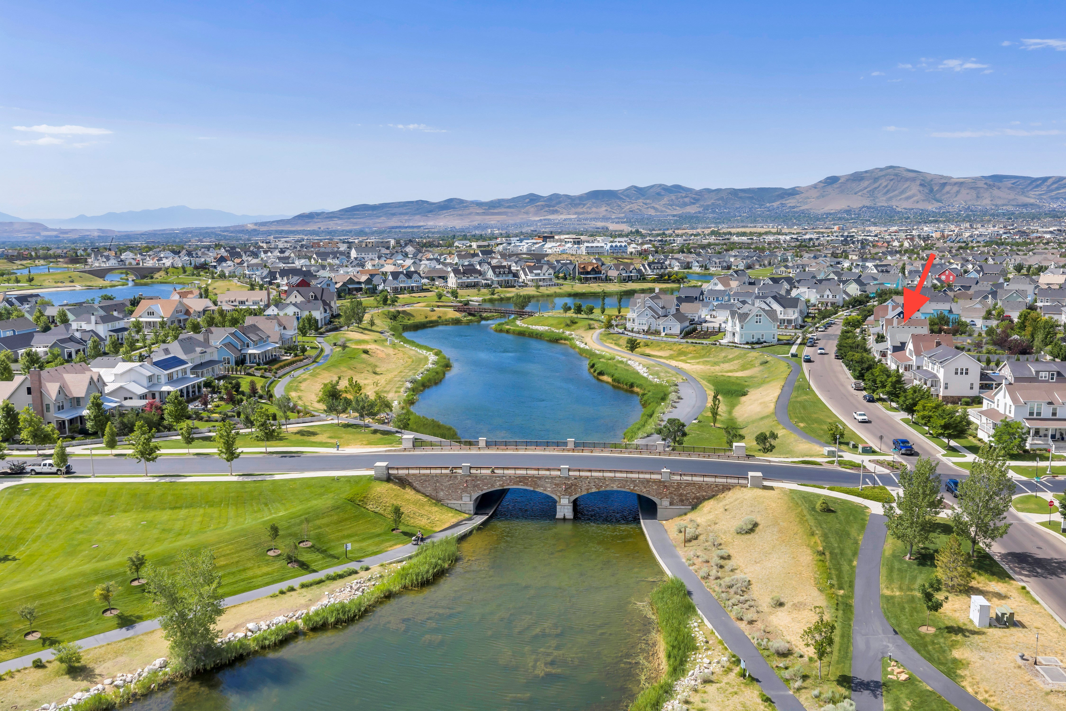 Expansive community with a central waterway, arched stone bridge, and paved pathways