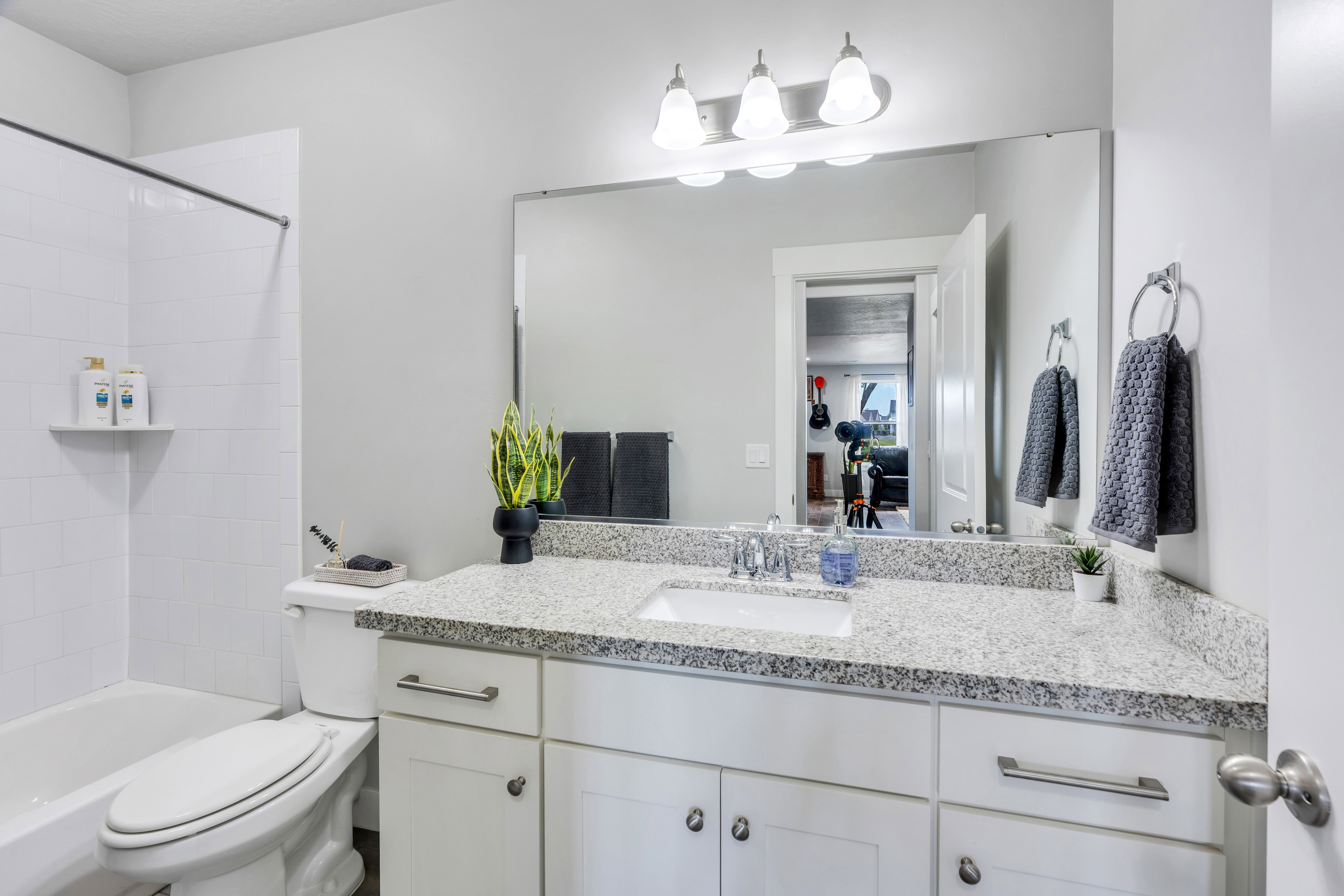 Bathroom featuring a white vanity with a light speckled countertop, an undermount sink, and a large wall-mounted mirror