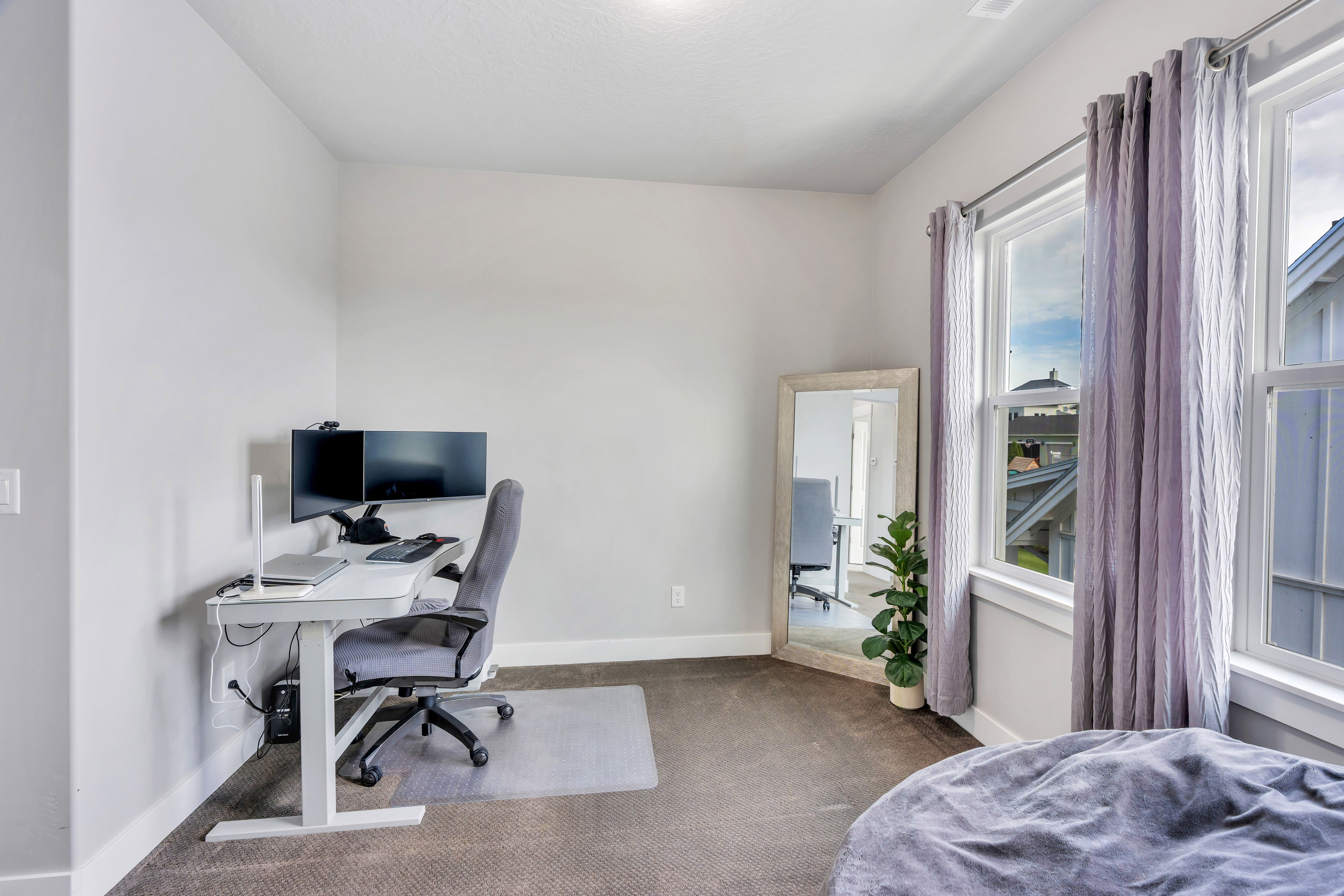 Carpeted room with light grey walls, white trim, and two large windows featuring white frames