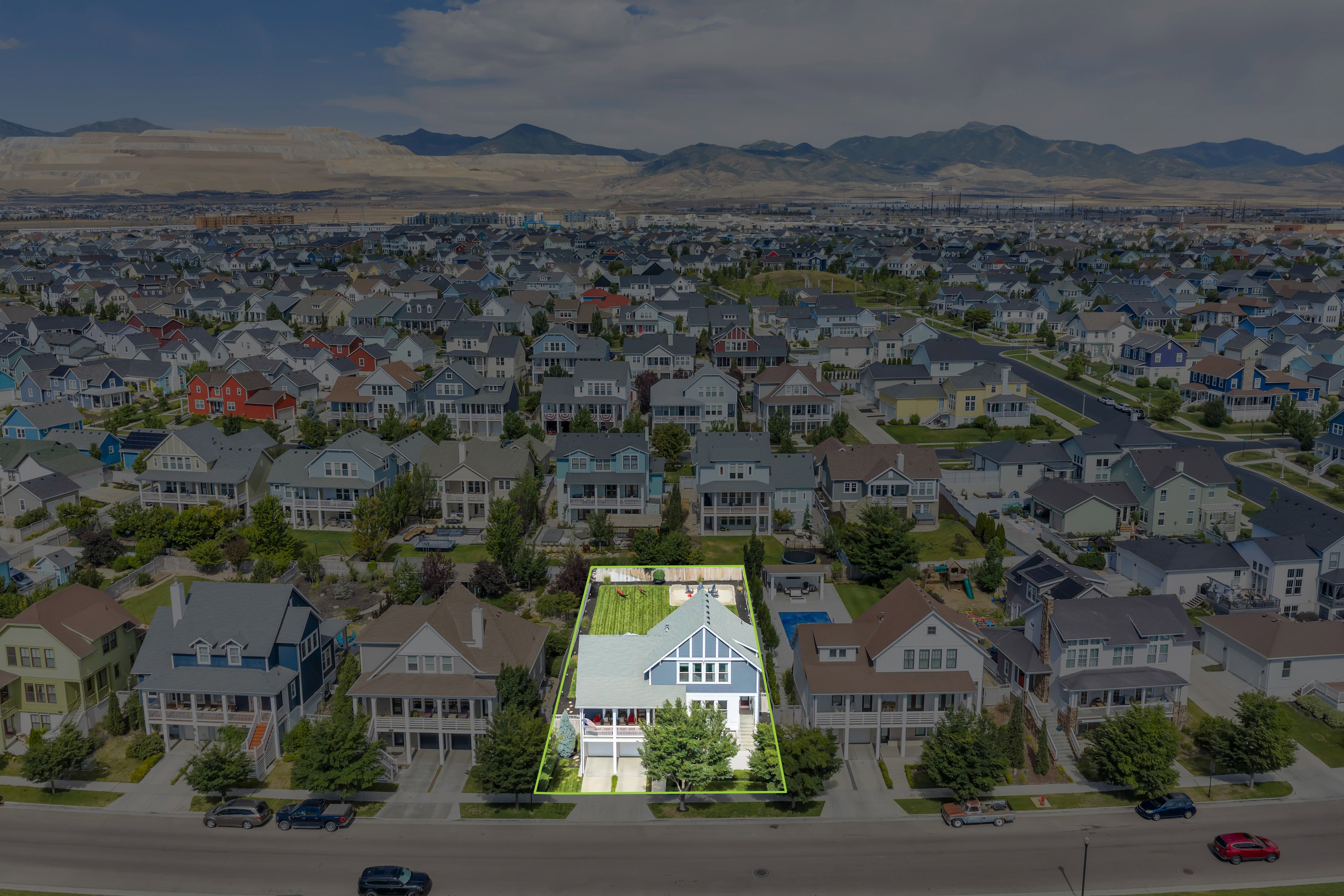 Aerial perspective highlighting a residential property with a light blue and white exterior, a gabled roofline, and a green, manicured rear yard