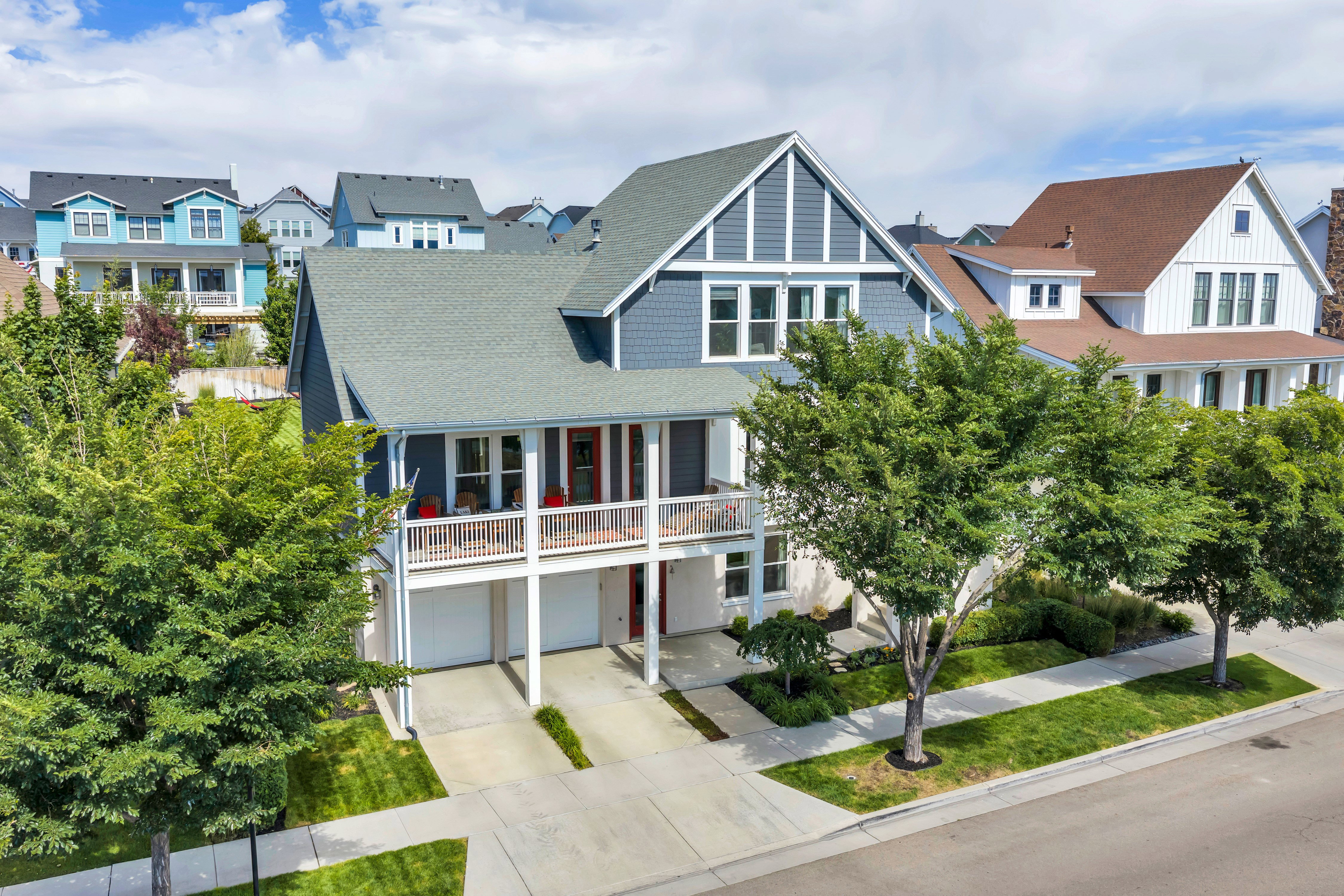 Two-story home featuring blue siding with white trim, a gabled roofline, and an upper-level balcony