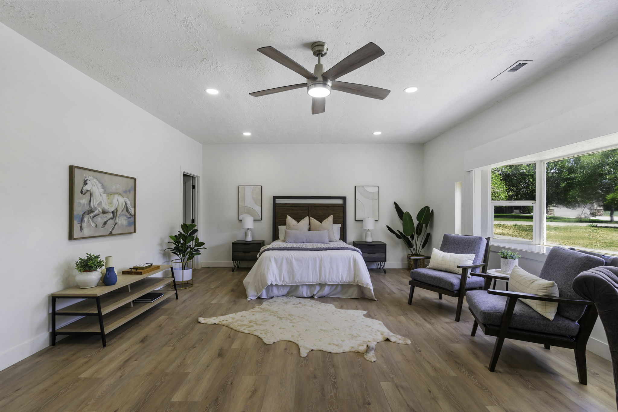 Spacious room featuring wood-finish flooring, a contemporary ceiling fan, recessed lighting, and expansive windows