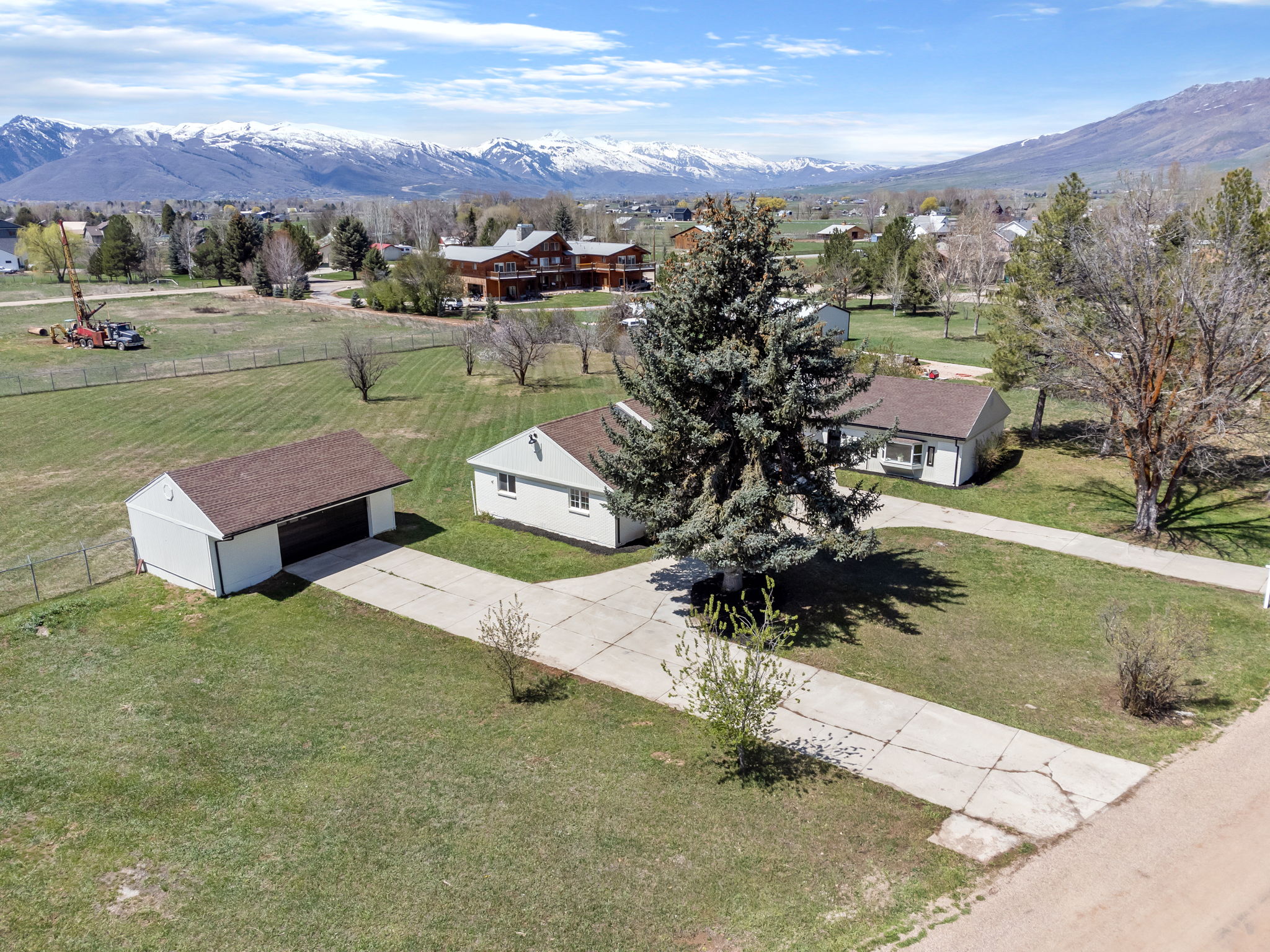 Property featuring a detached garage, expansive green lawn, and concrete driveway
