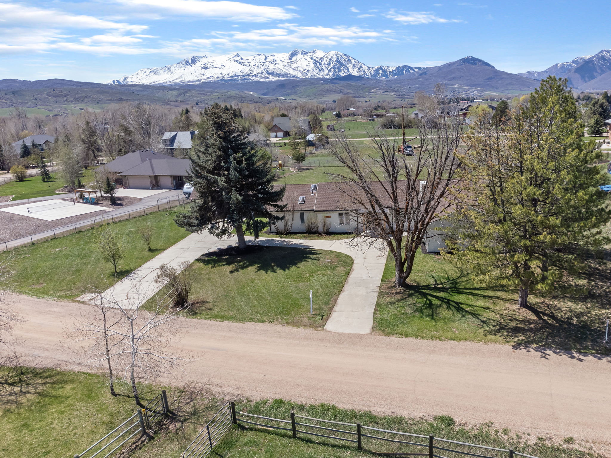 Expansive property featuring a paved driveway, mature trees, and a spacious lawn