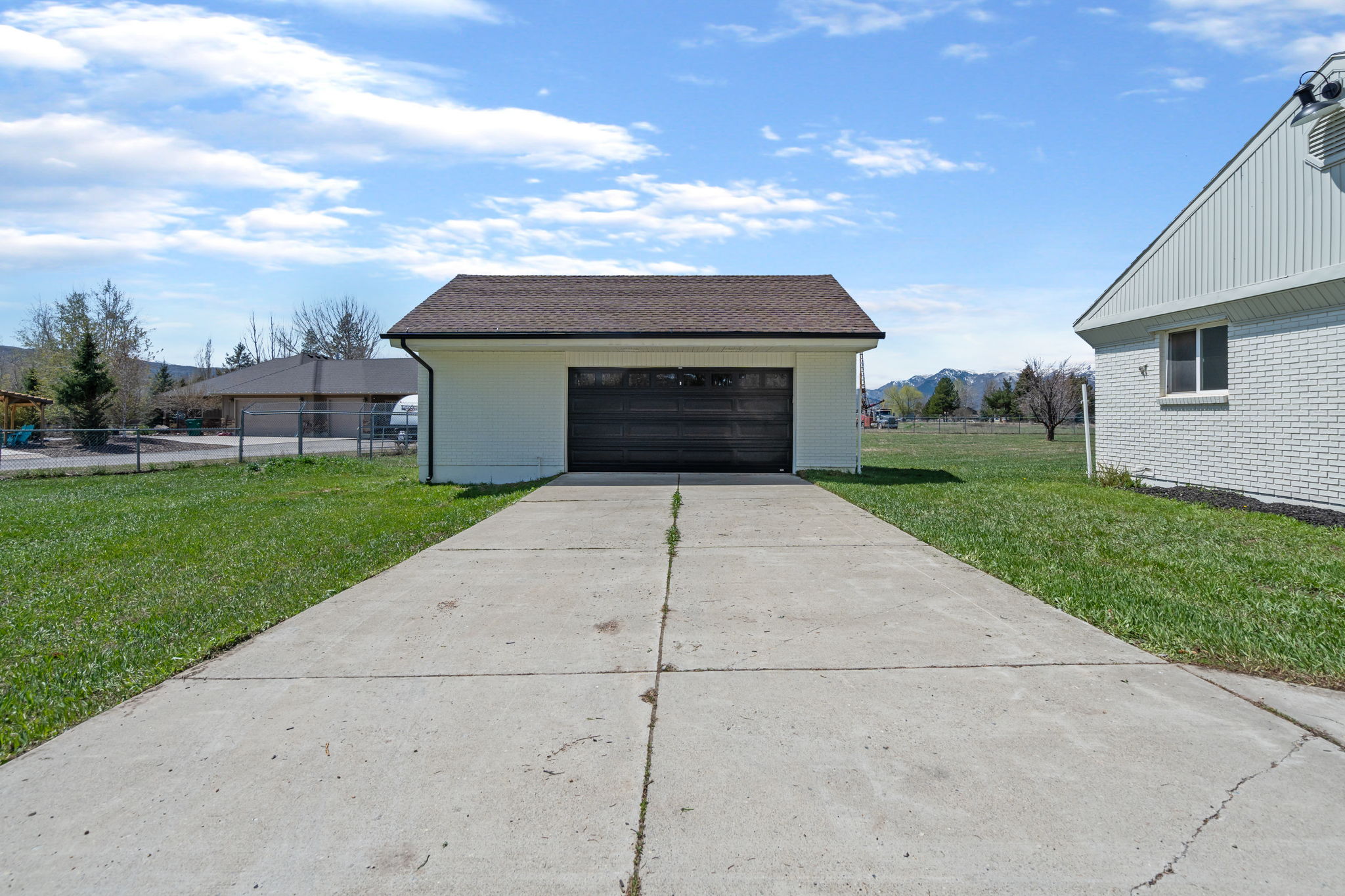 Detached two-car garage with a dark panel garage door and white exterior siding