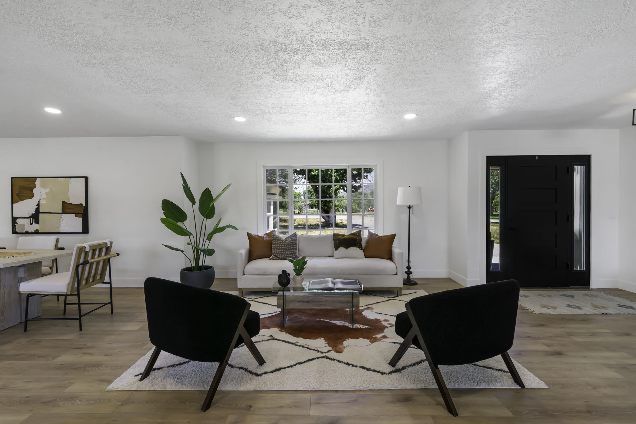 Bright living space featuring wood-finish flooring, a contemporary front entry door with sidelights, recessed lighting, and a multi-pane window