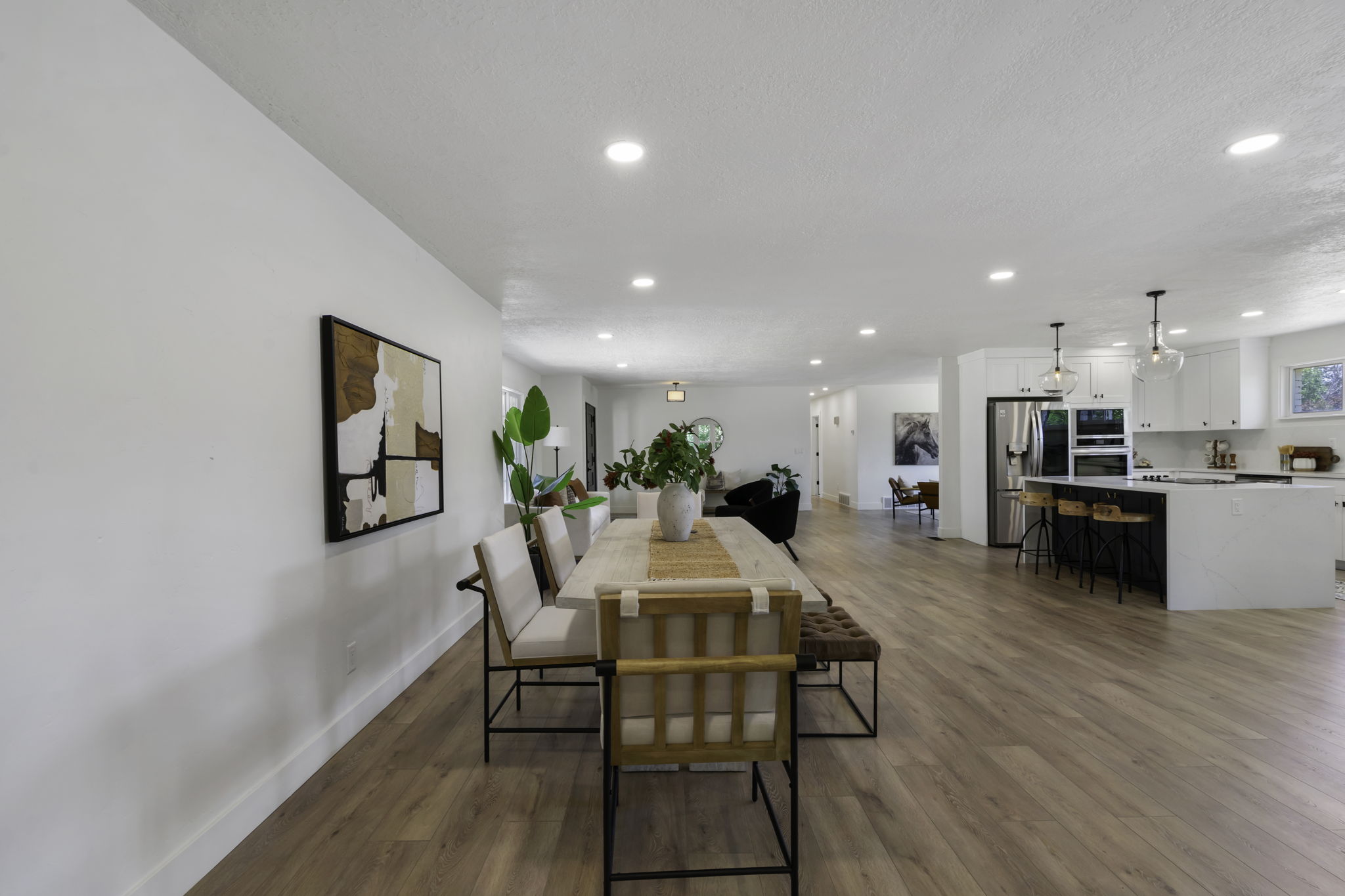 Open-concept living space featuring wood-finish flooring, recessed lighting, and a white color palette