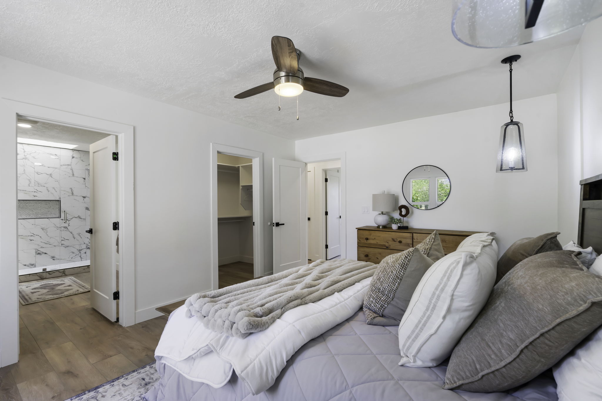 Bedroom with wood-finish flooring, a ceiling fan with integrated lighting, and a contemporary pendant light fixture