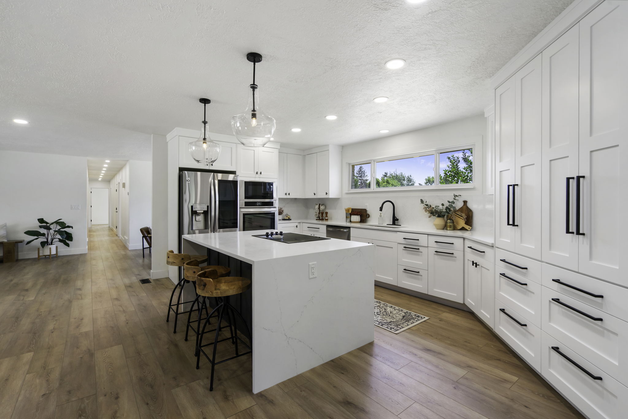Open-concept kitchen featuring an oversized island with seating, a smooth cooktop, and quartz countertops
