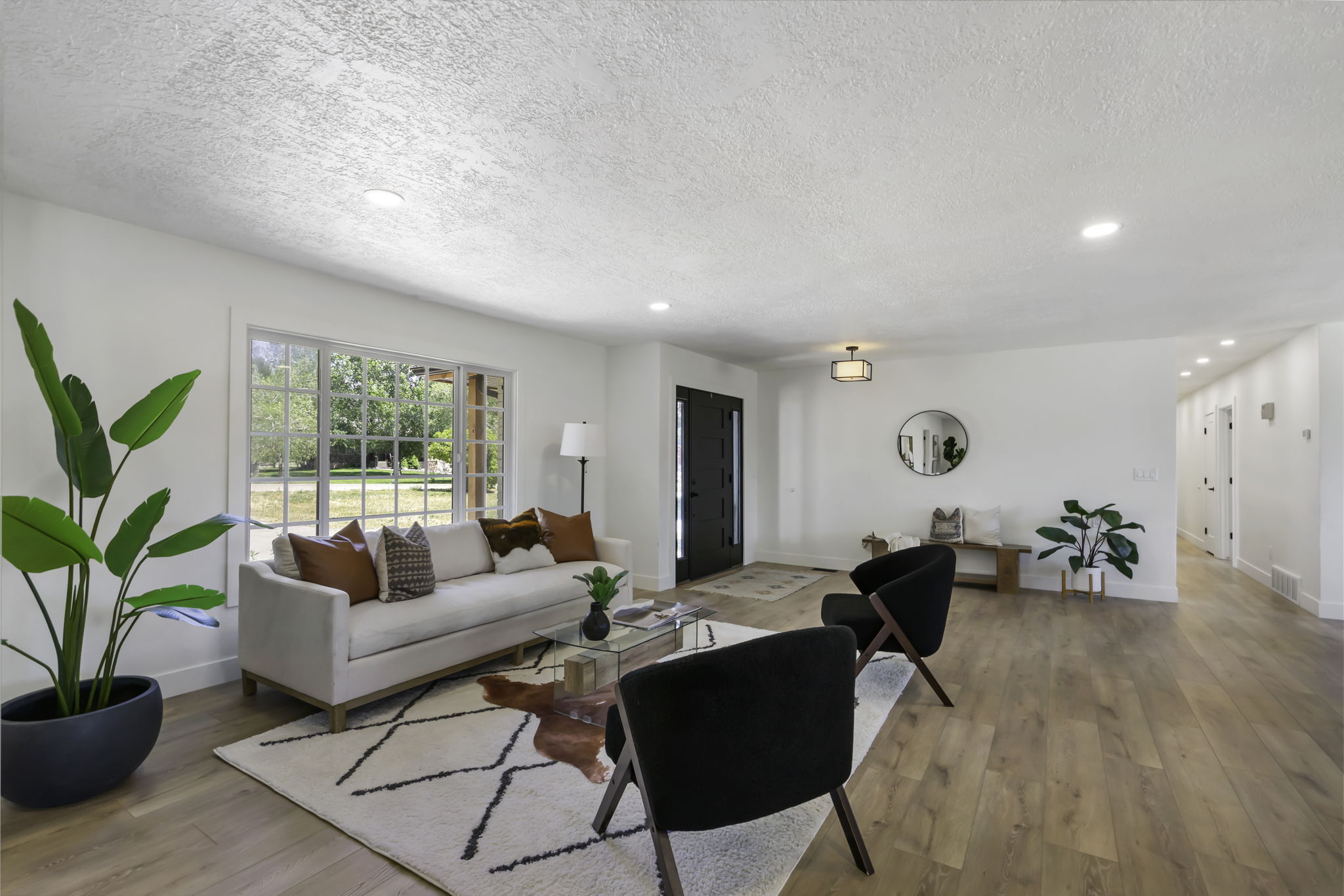 Open-concept living space featuring wood-finish flooring, recessed lighting, and a large picture window with grid detailing