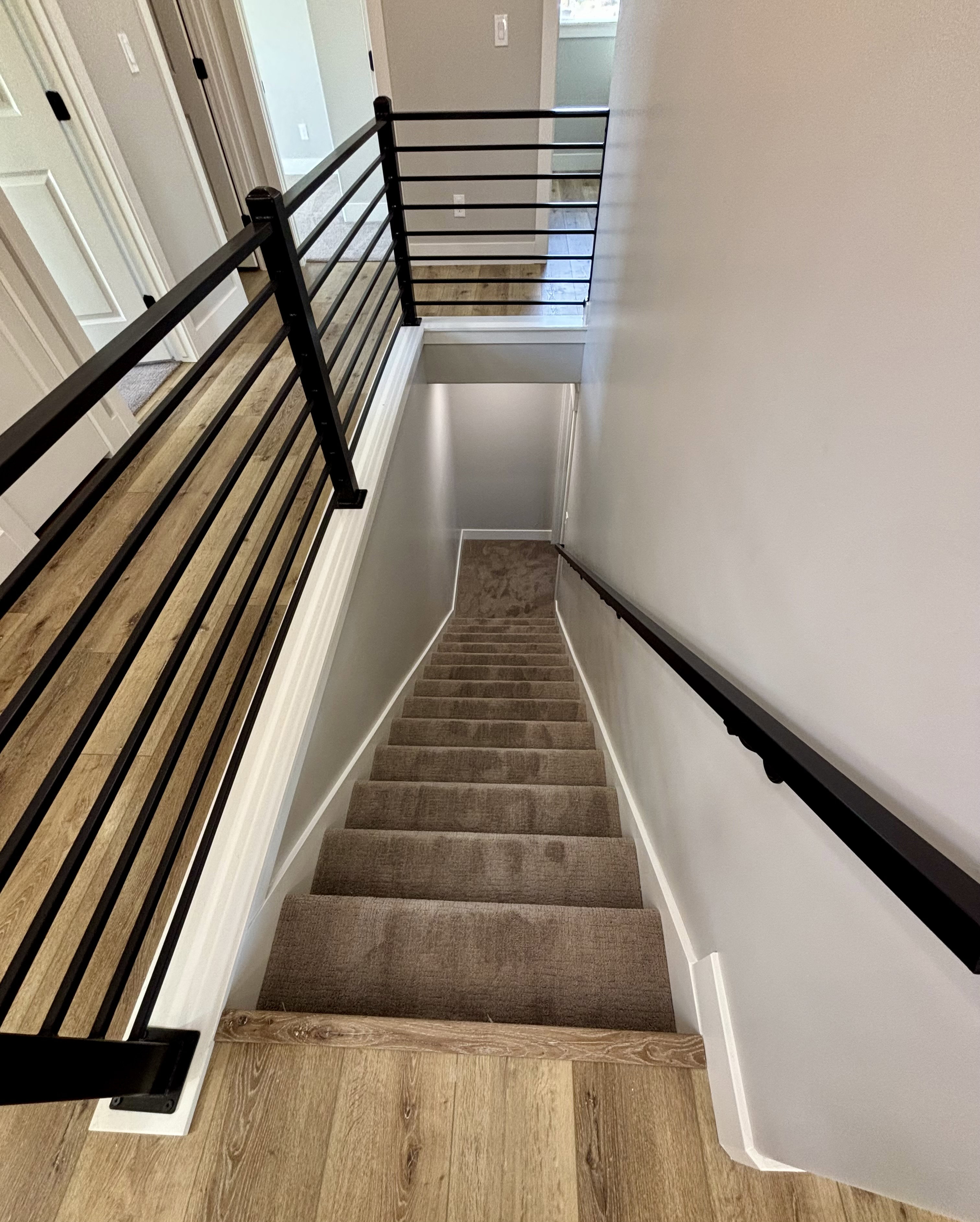 Staircase featuring contemporary horizontal metal railings, wood-finish flooring, and light gray wall paint
