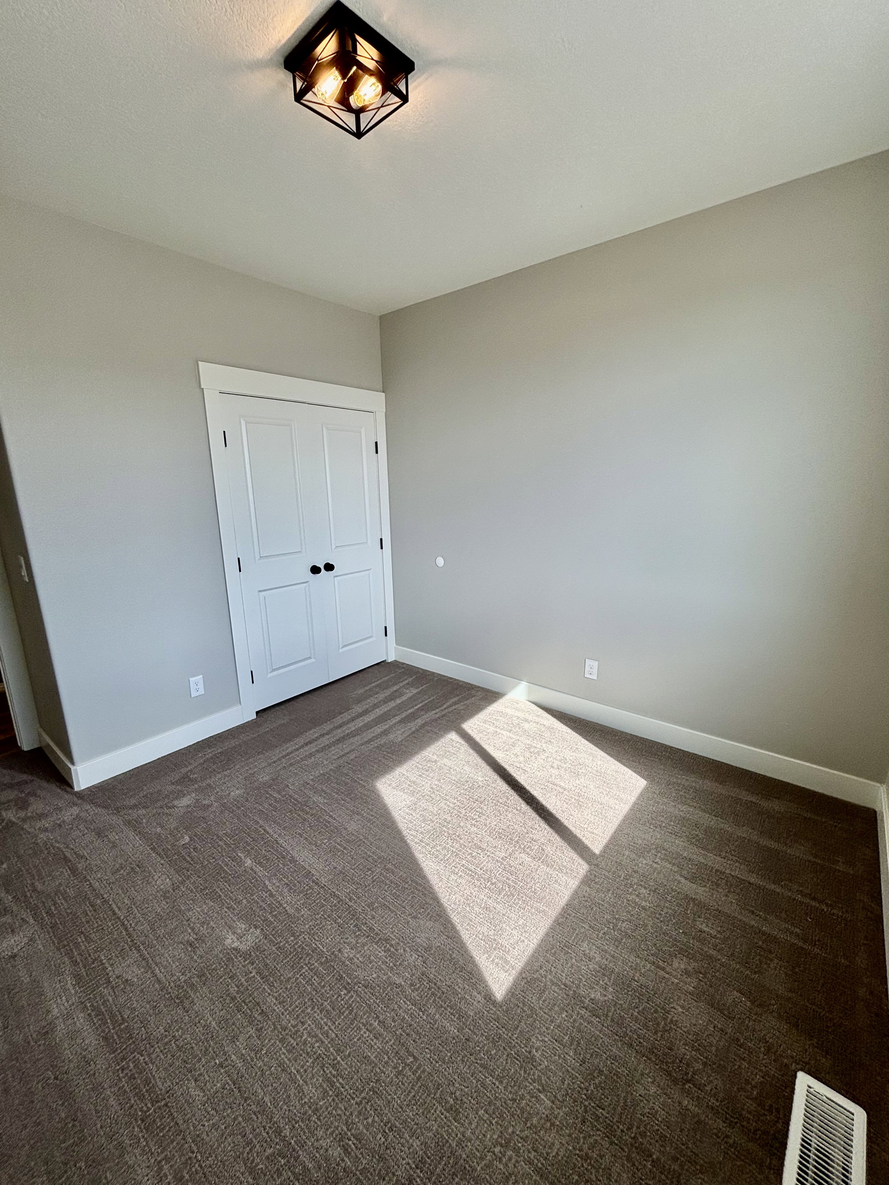 Neutral-toned room featuring a dark brown patterned carpet, white baseboards, and a white bi-fold closet door