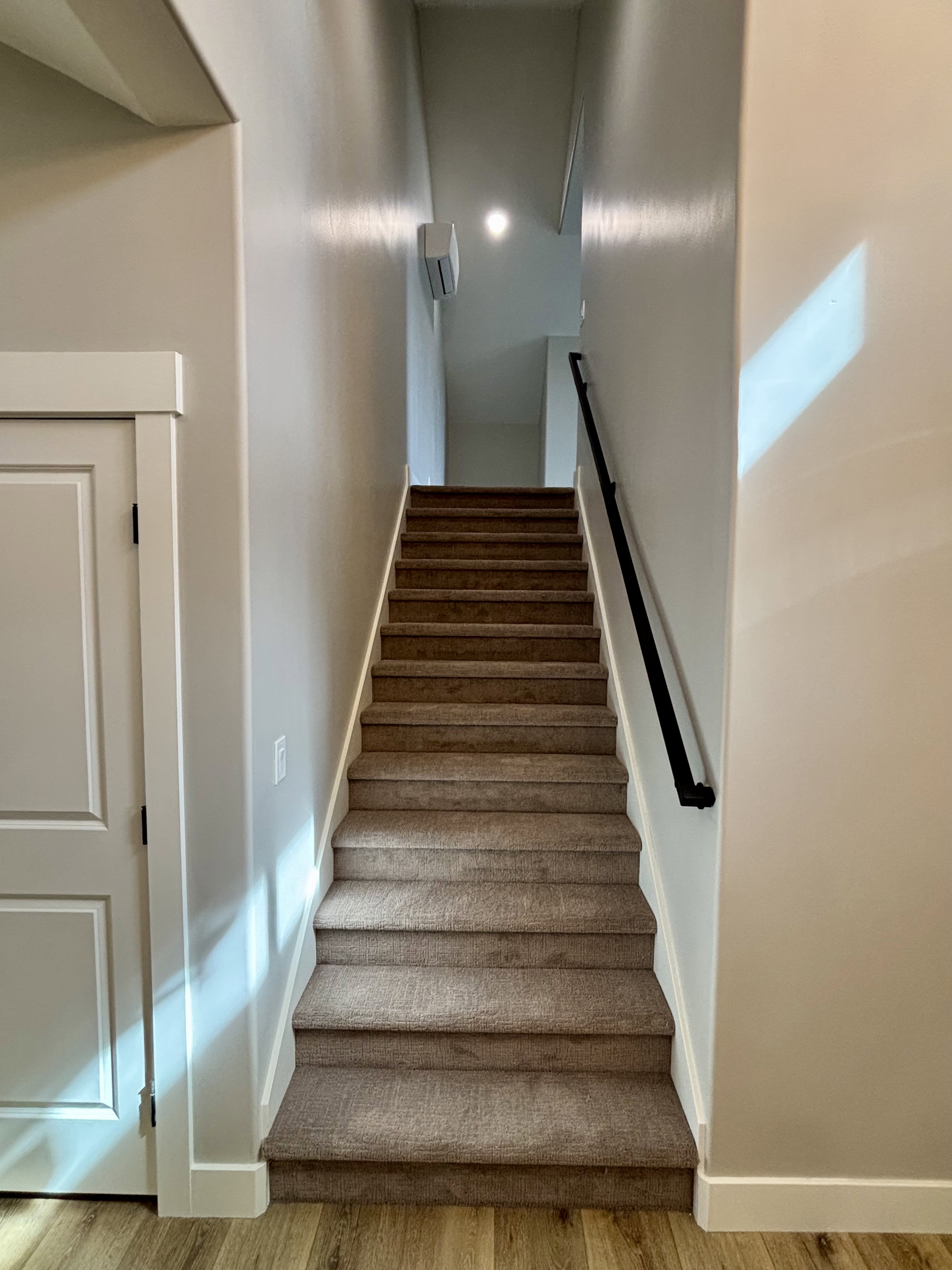 Carpeted staircase featuring a matte black handrail, recessed lighting, and a wall-mounted mini-split unit