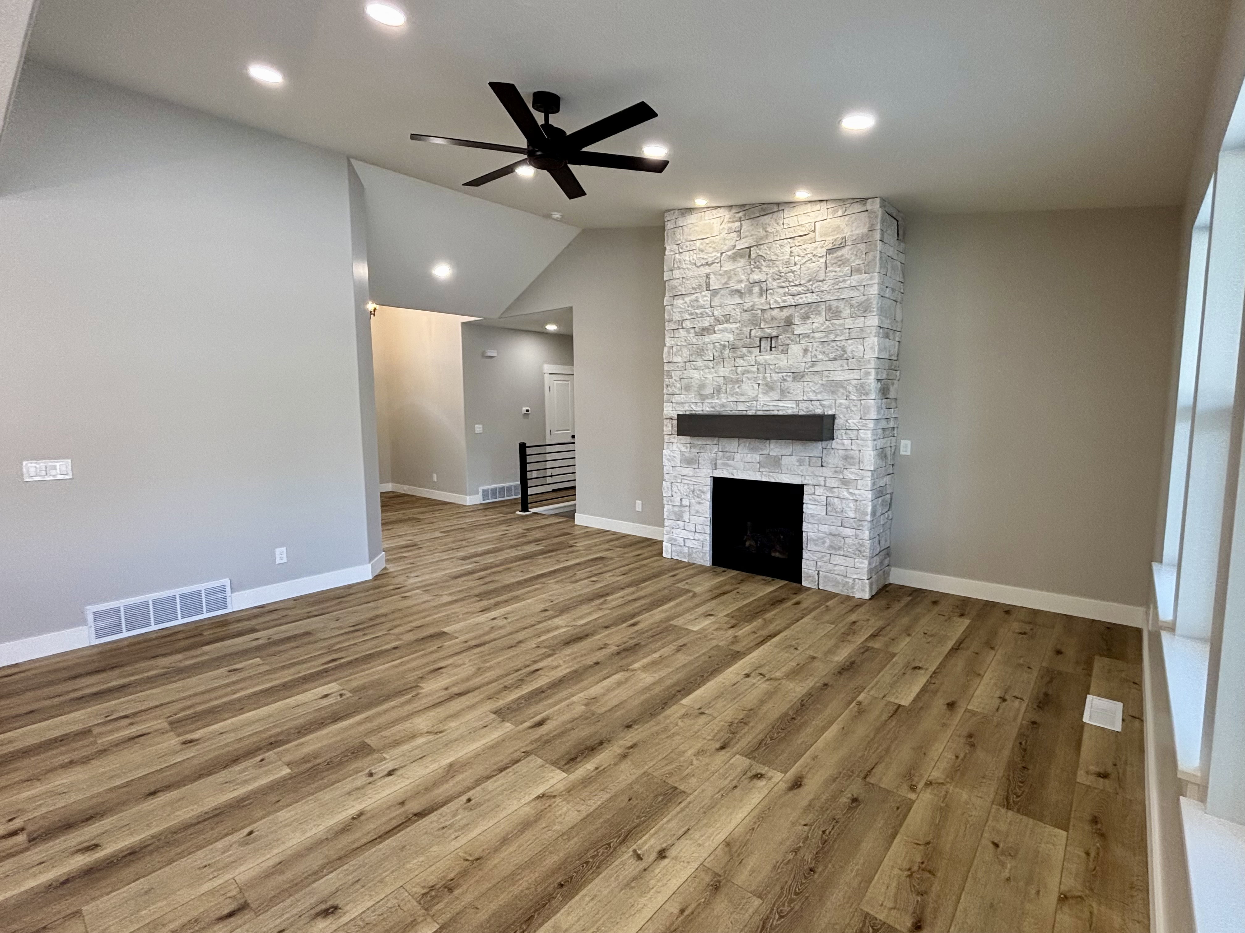 Living space featuring a stacked stone fireplace with a dark wood mantel and a black fireplace