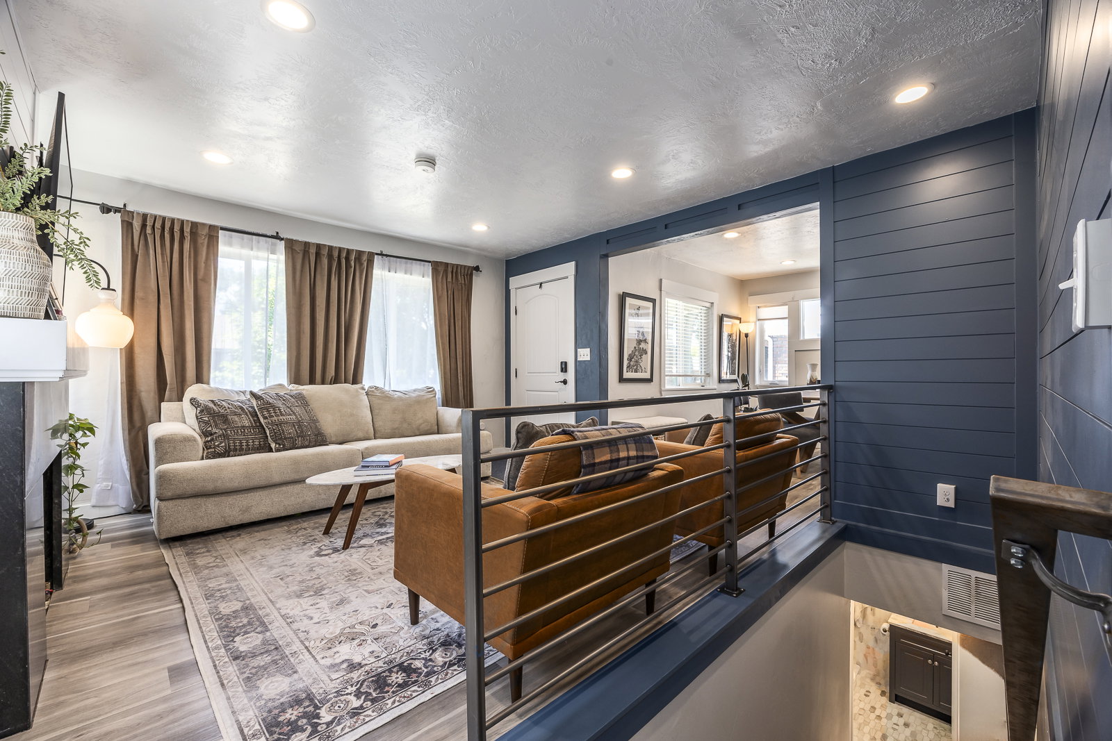 Open living space featuring wood-finish flooring, recessed lighting, and a contemporary railing