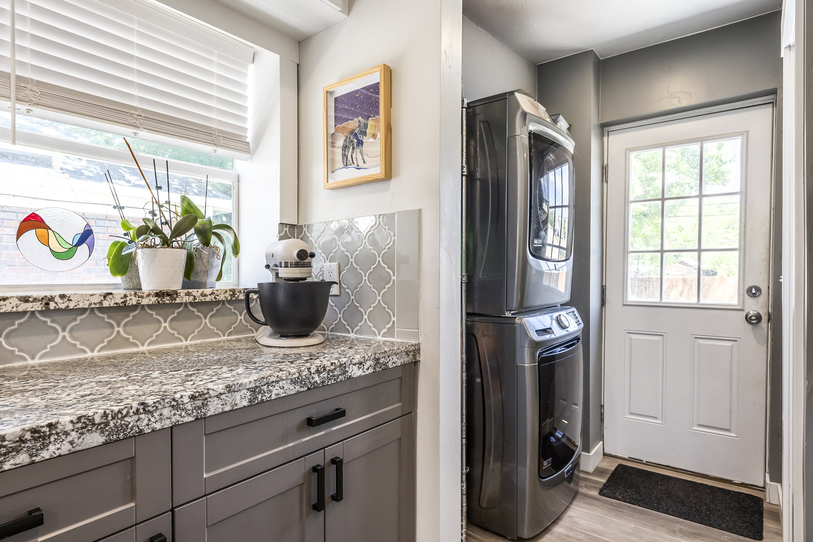 Functional utility area featuring a stacked washer and dryer unit, wood-finish flooring, and a glass-paneled exterior door