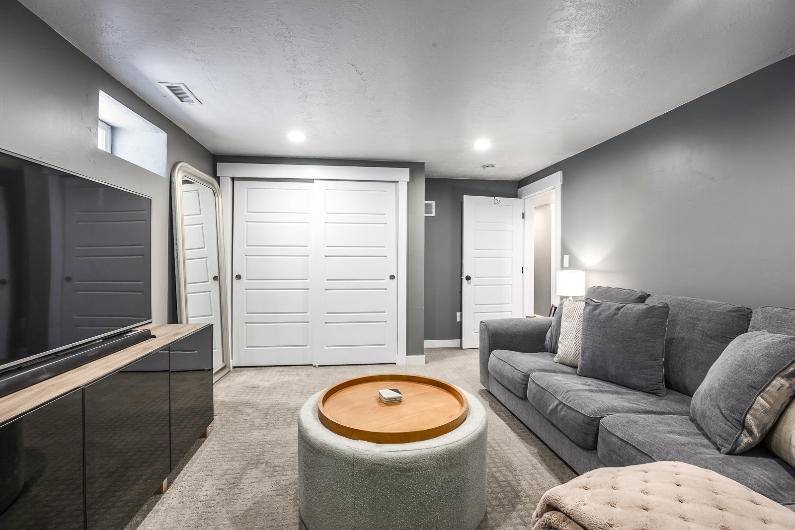 Carpeted living area featuring recessed lighting, a window, white sliding doors, and white paneled doors with black hardware