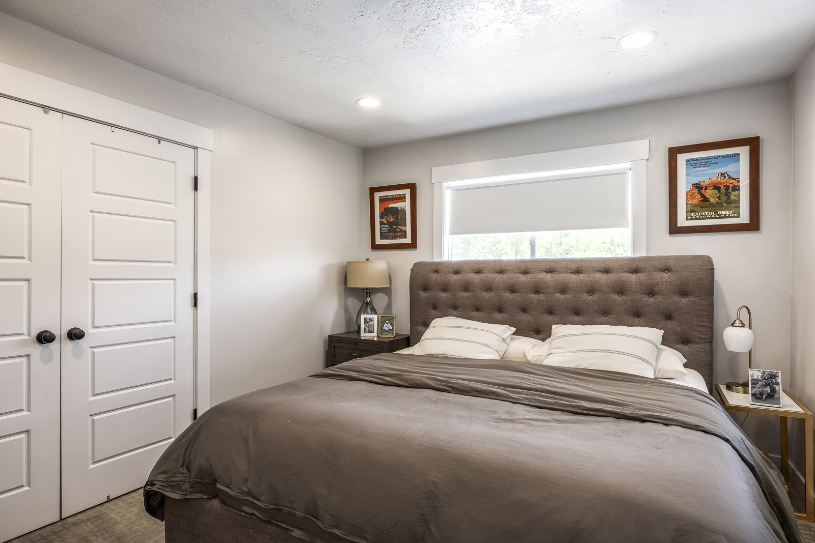 Neutral-toned bedroom featuring a window with a roller shade, recessed lighting, and a paneled double-door closet with dark hardware