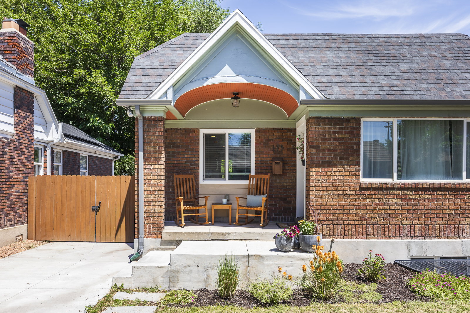 Brick facade home with a covered front porch featuring an arched ceiling detail, a gabled roofline, and an asphalt shingle roof