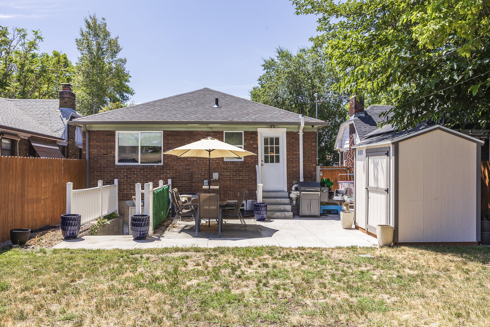 Rear exterior featuring brick siding, a dark shingle roof, and a white entry door with glass panes
