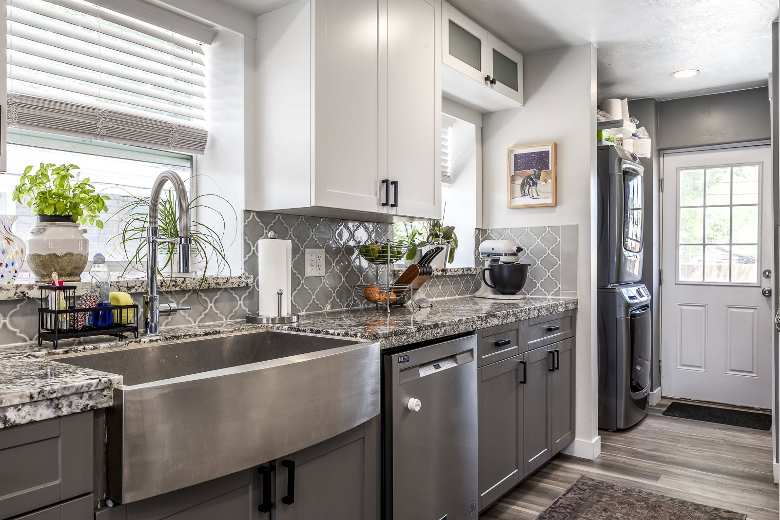Kitchen featuring a stainless steel farmhouse sink with a gooseneck faucet, granite countertops, and a gray arabesque tile backsplash